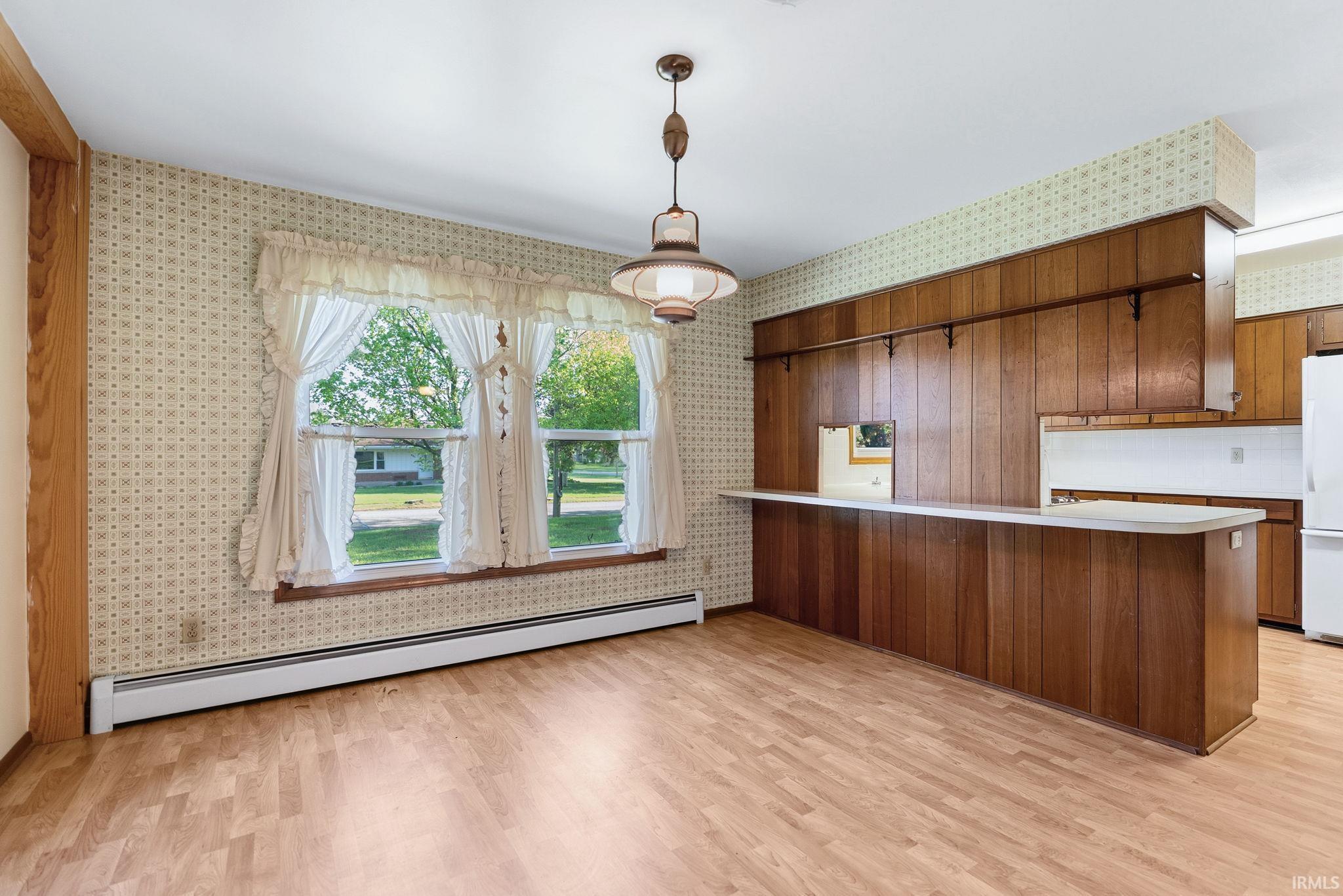 Open-concept living area featuring wood-finish flooring, a wood-paneled breakfast bar, and an exposed wood beam