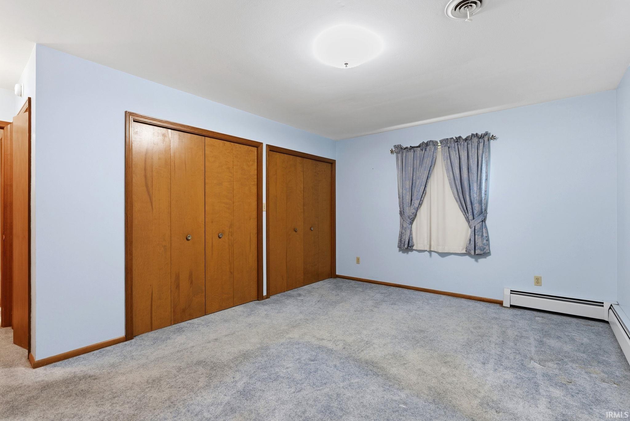 Room featuring light blue walls, gray carpet, and two sets of bi-fold wooden closet doors
