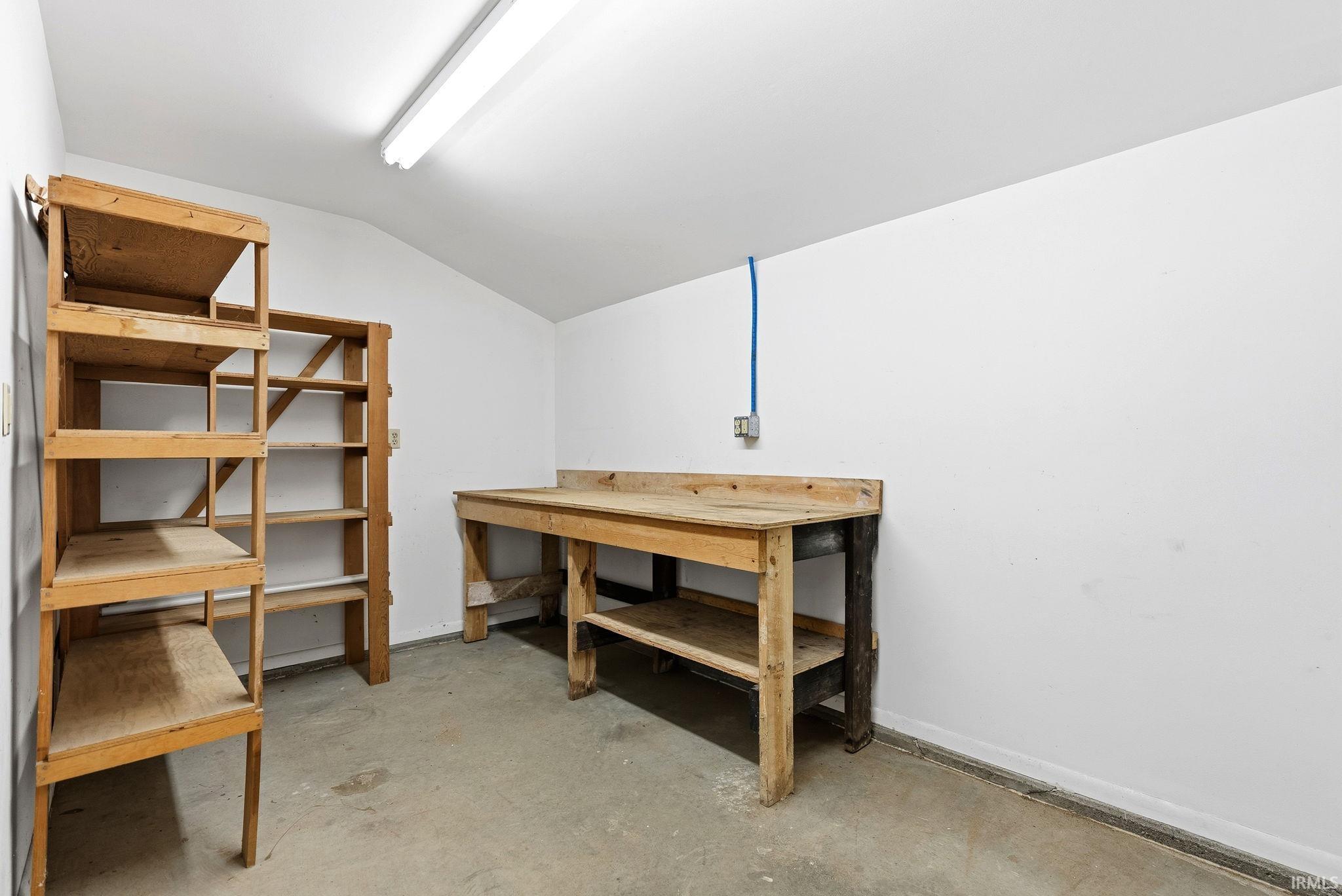 Storage area with concrete flooring, white painted walls, and an angled ceiling
