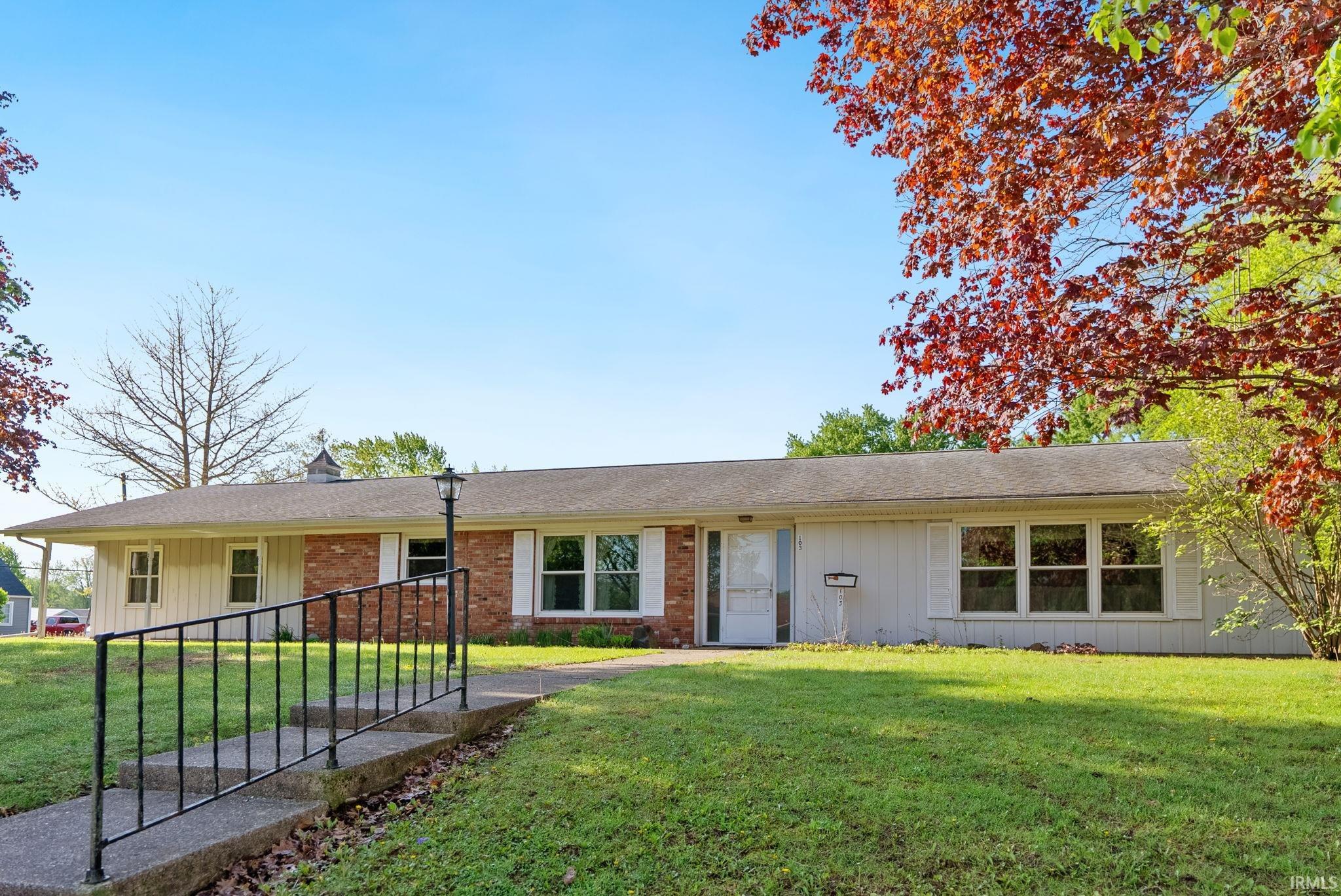 Ranch-style residence featuring a brick facade, white siding, and a gabled roofline