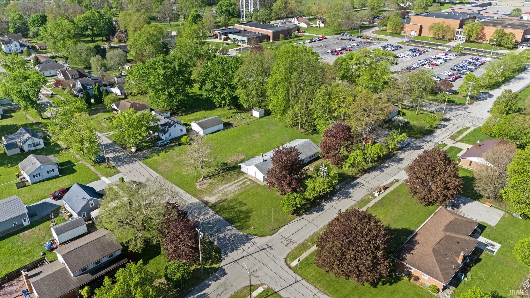 Expansive land parcel featuring existing structures, mature trees, and a surrounding residential area