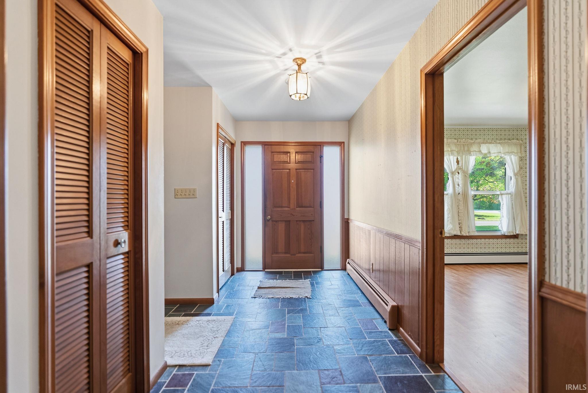 Foyer featuring dark square tile flooring and a solid wood entry door with sidelights