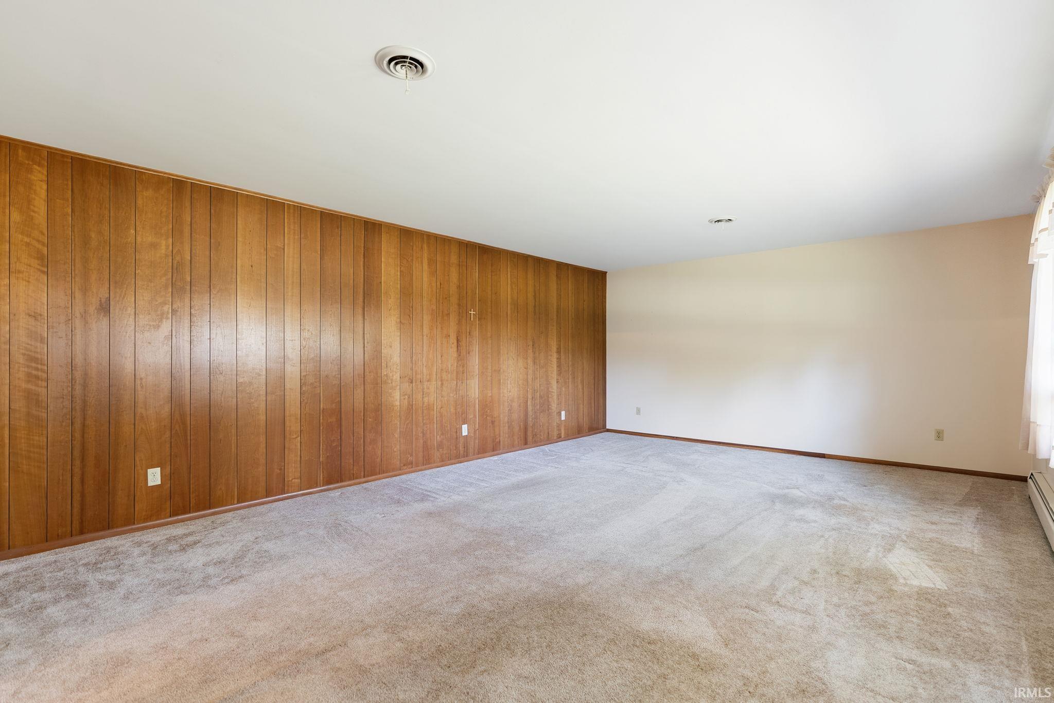 Spacious room featuring wood paneling along one wall and neutral-toned painted walls