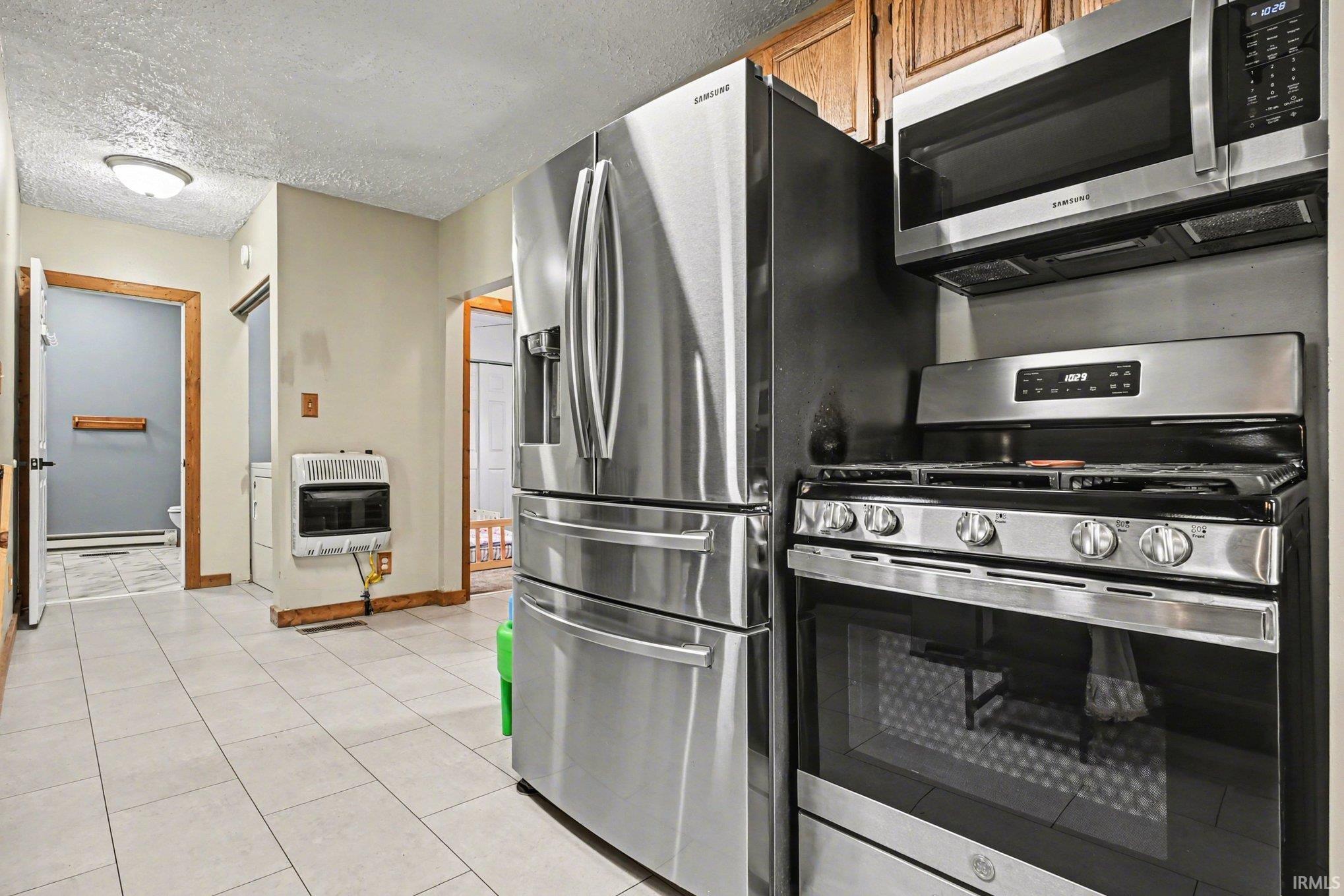 Kitchen space featuring stainless steel appliances, including a side-by-side refrigerator, gas range, and microwave