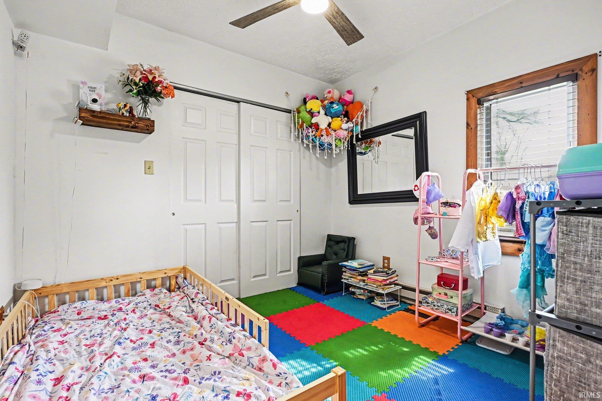 Bright room featuring a ceiling fan, white walls, and a window with wood trim
