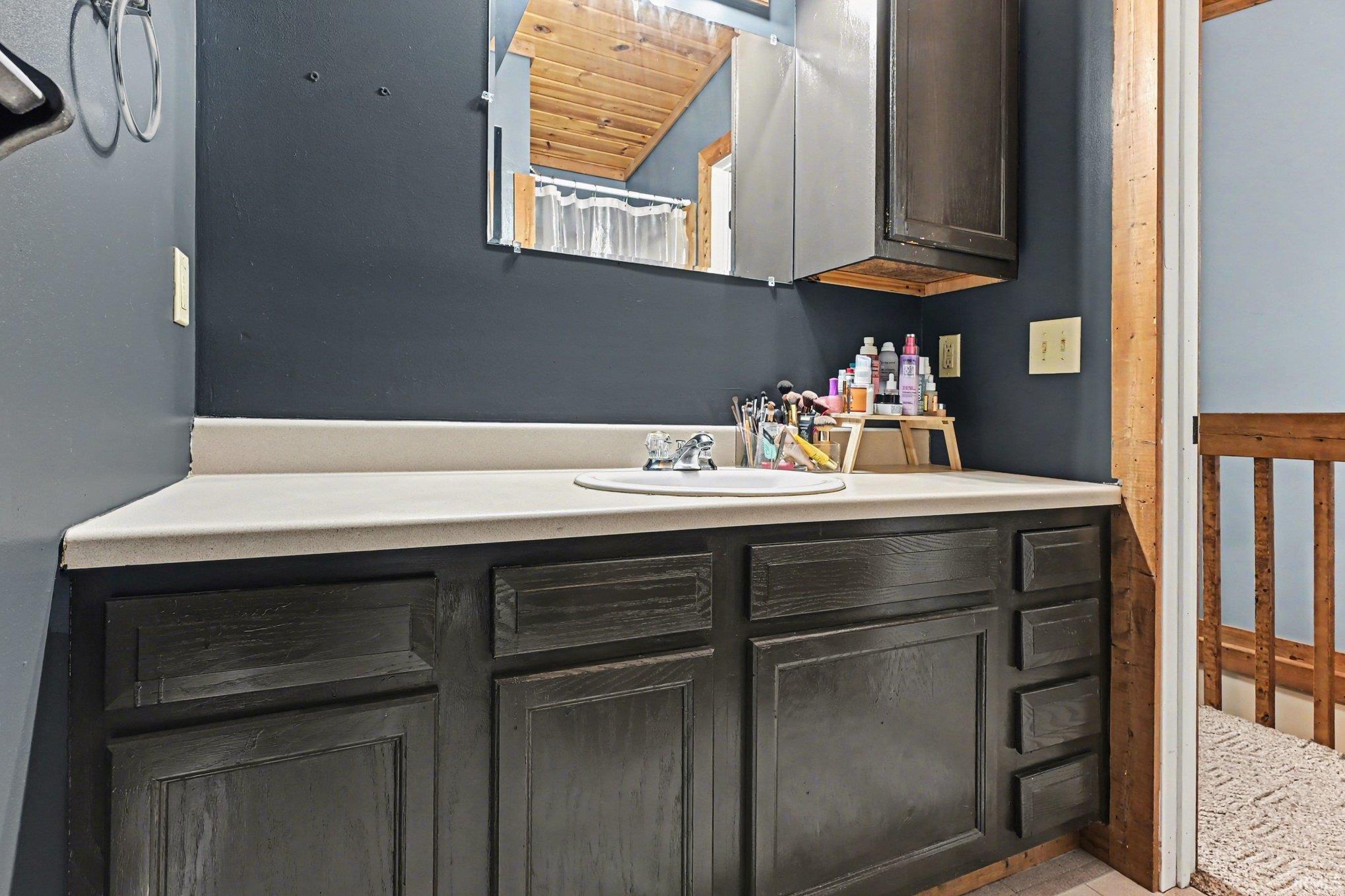 Bathroom vanity featuring a light-colored countertop, integrated sink, and dark wood-finish cabinetry