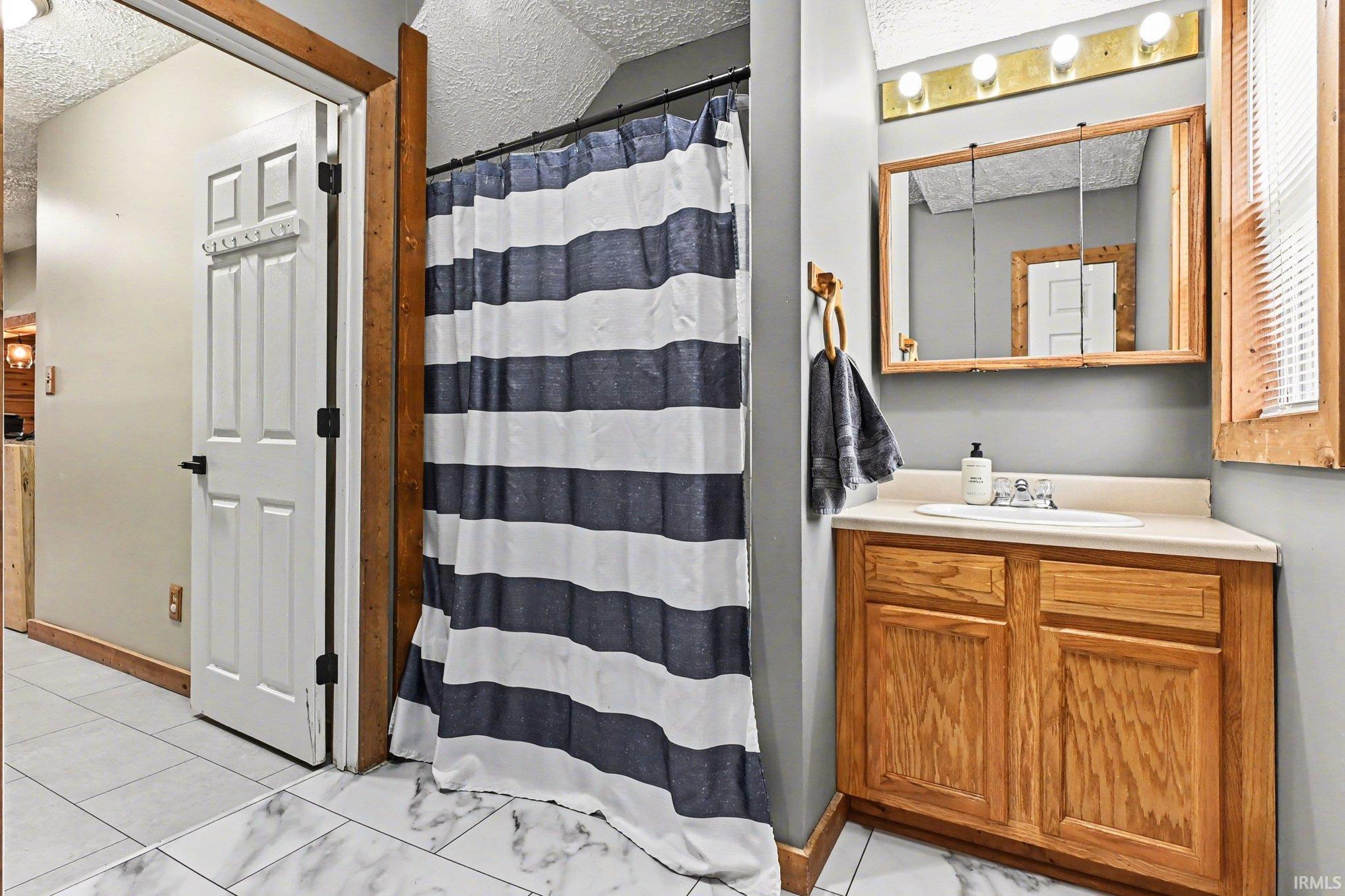 Full bathroom featuring a single vanity with wood cabinetry, a built-in sink, and a framed medicine cabinet