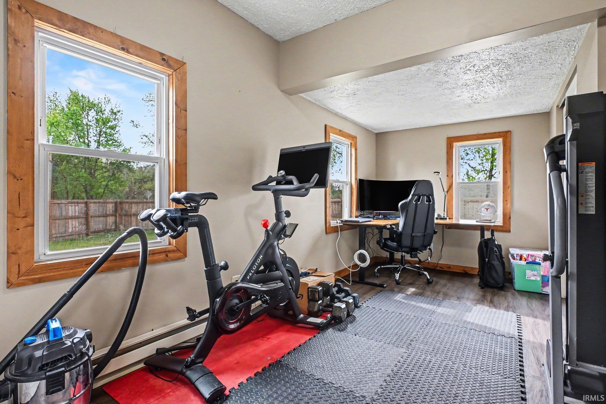 Versatile room featuring two windows with natural wood trim, wood-finish flooring, and ample space for various uses