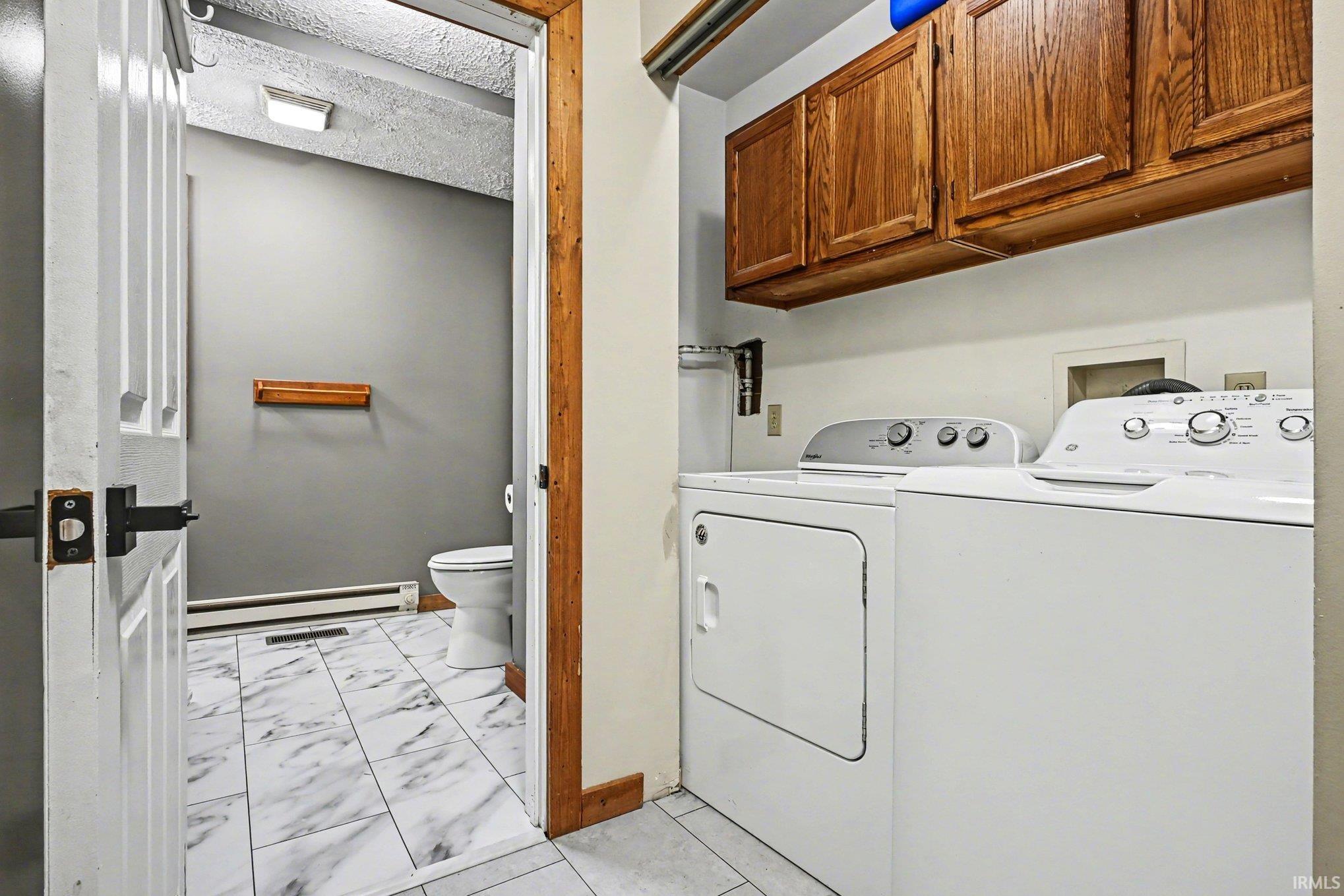 Dedicated laundry area with upper wood cabinetry and side-by-side appliances