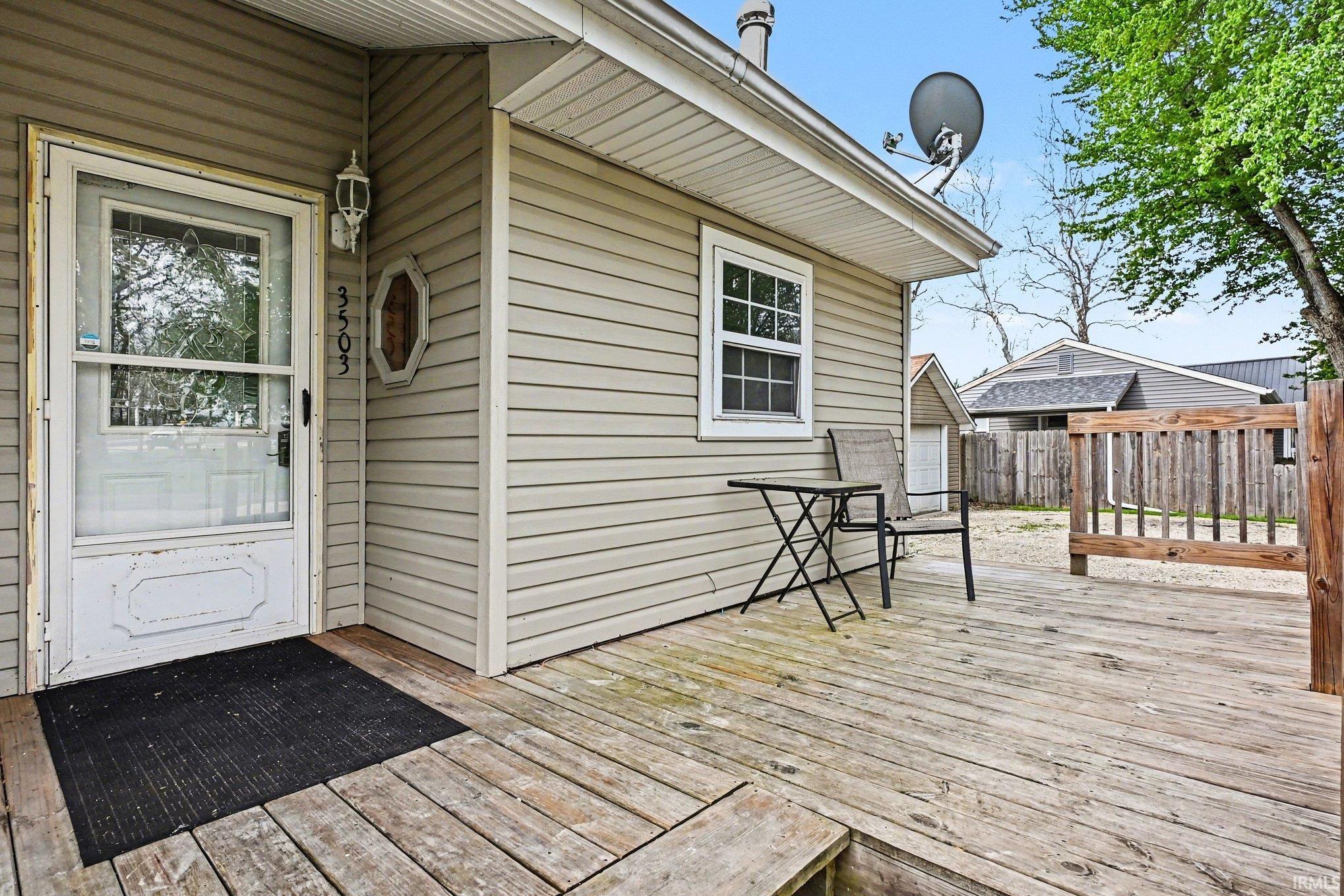Front entrance with a storm door, an exterior wall light fixture, and horizontal siding