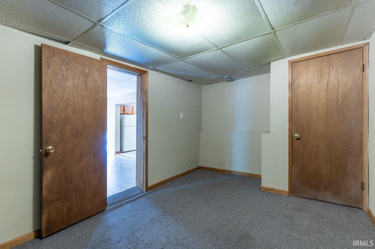 Interior room featuring textured acoustic ceiling tiles, light-toned wall paint, and gray carpet flooring