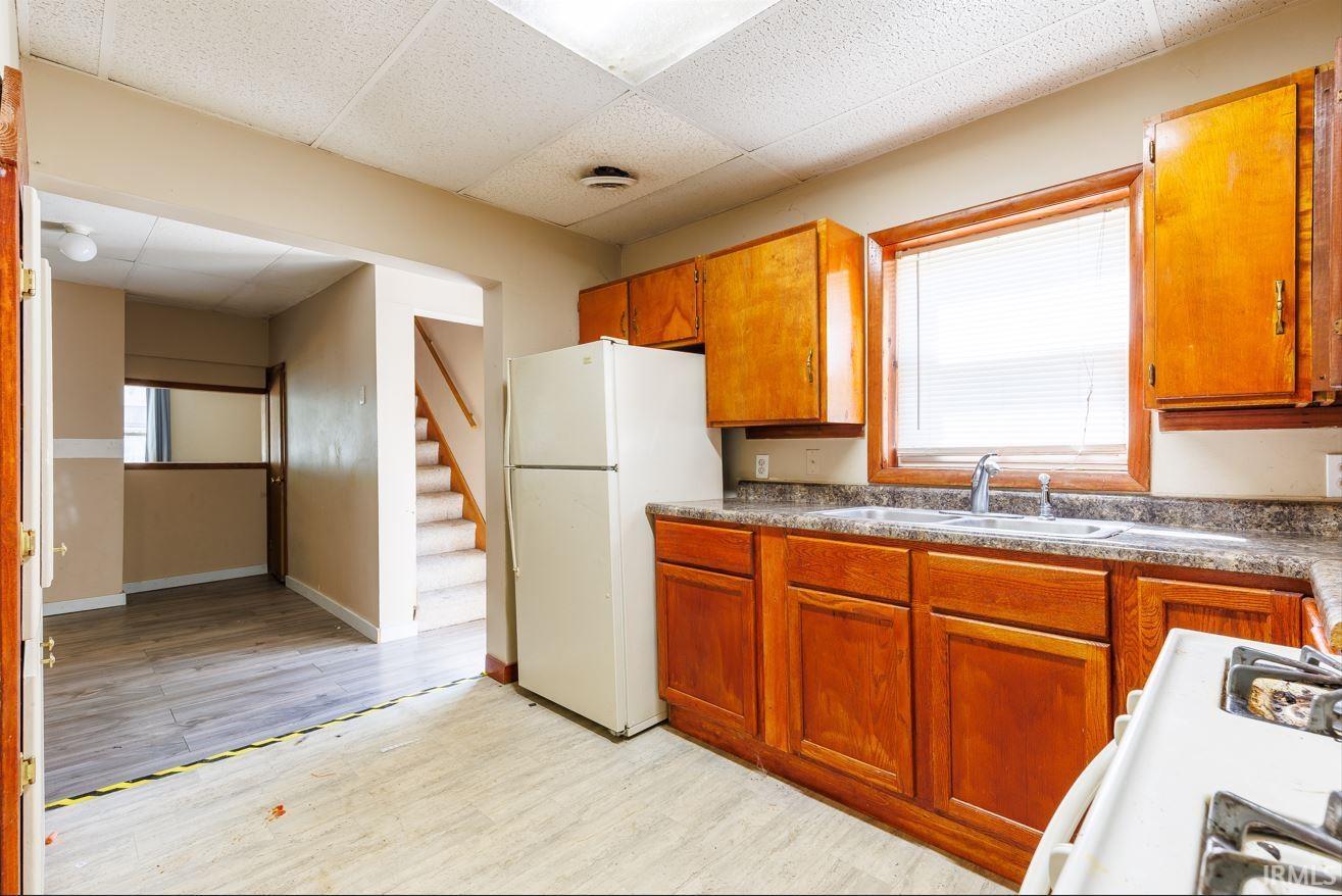 Kitchen featuring wood cabinetry, laminate countertops, a double basin sink, and a window with blinds