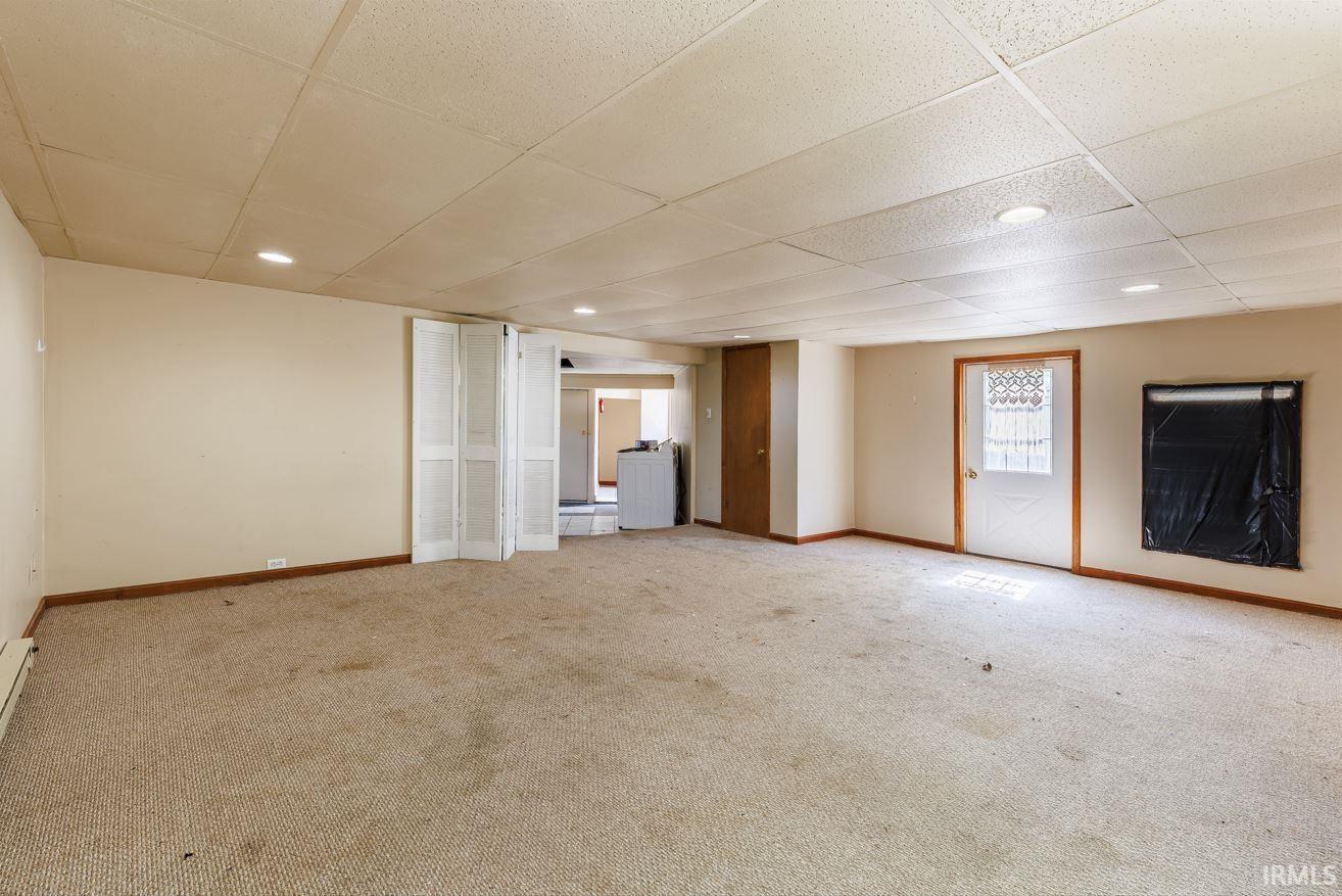 Spacious room featuring carpet flooring, painted walls, and a drop ceiling with recessed lighting