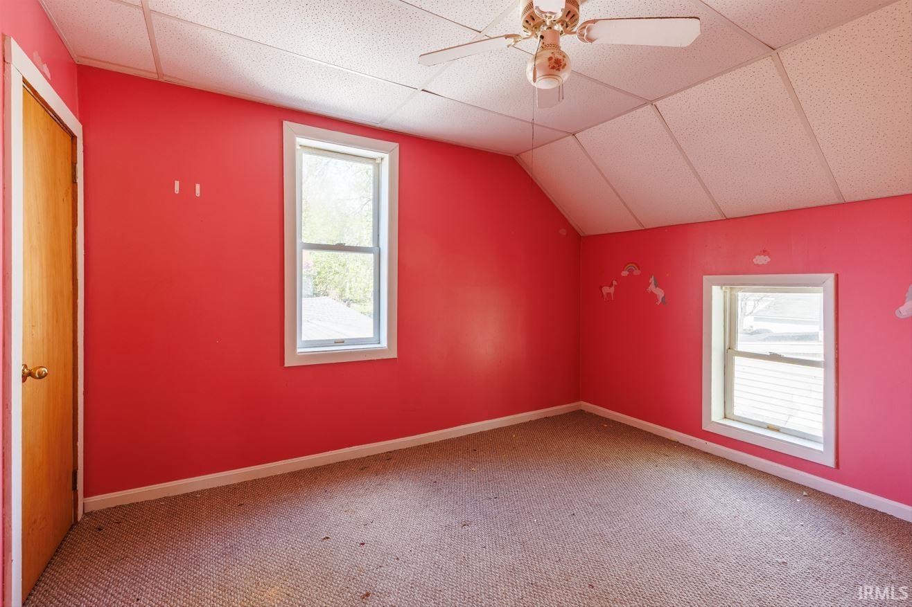 Interior room with two windows, sloped ceiling, and a ceiling fan