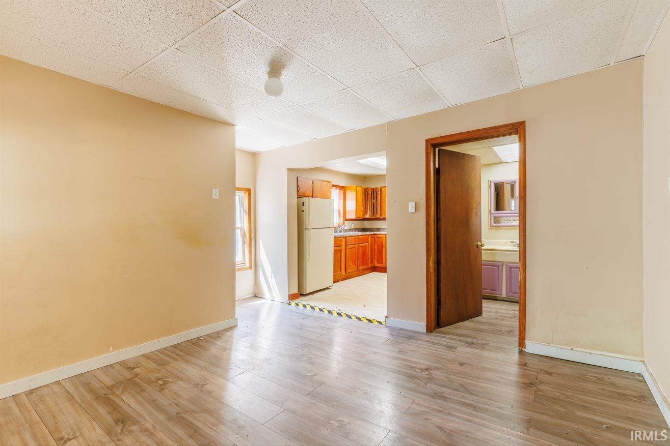 Open-concept living area featuring wood-finish flooring, a neutral color palette, and a paneled ceiling