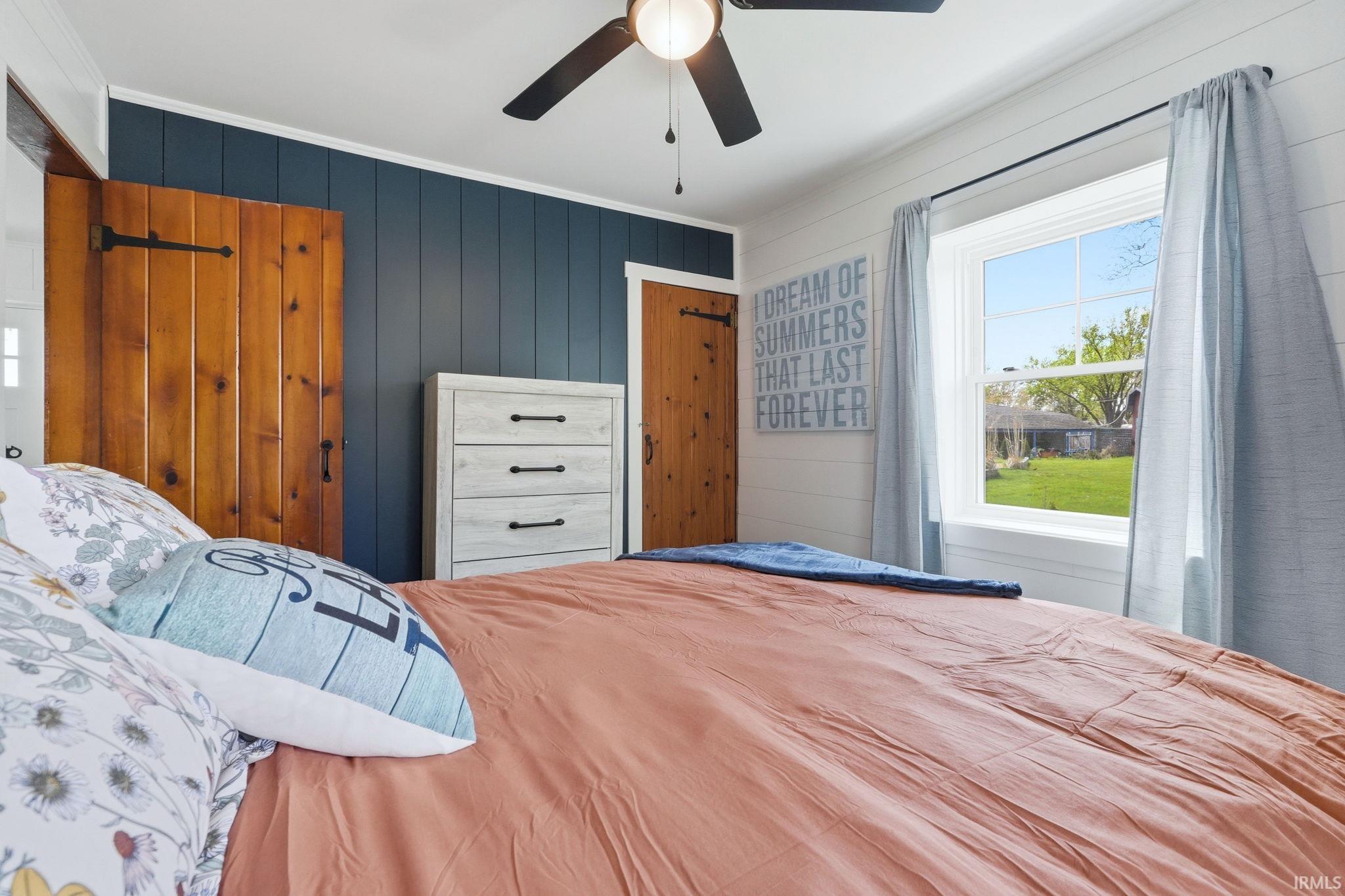 Room featuring shiplap wall paneling, a ceiling fan with light fixture, and a window providing natural illumination
