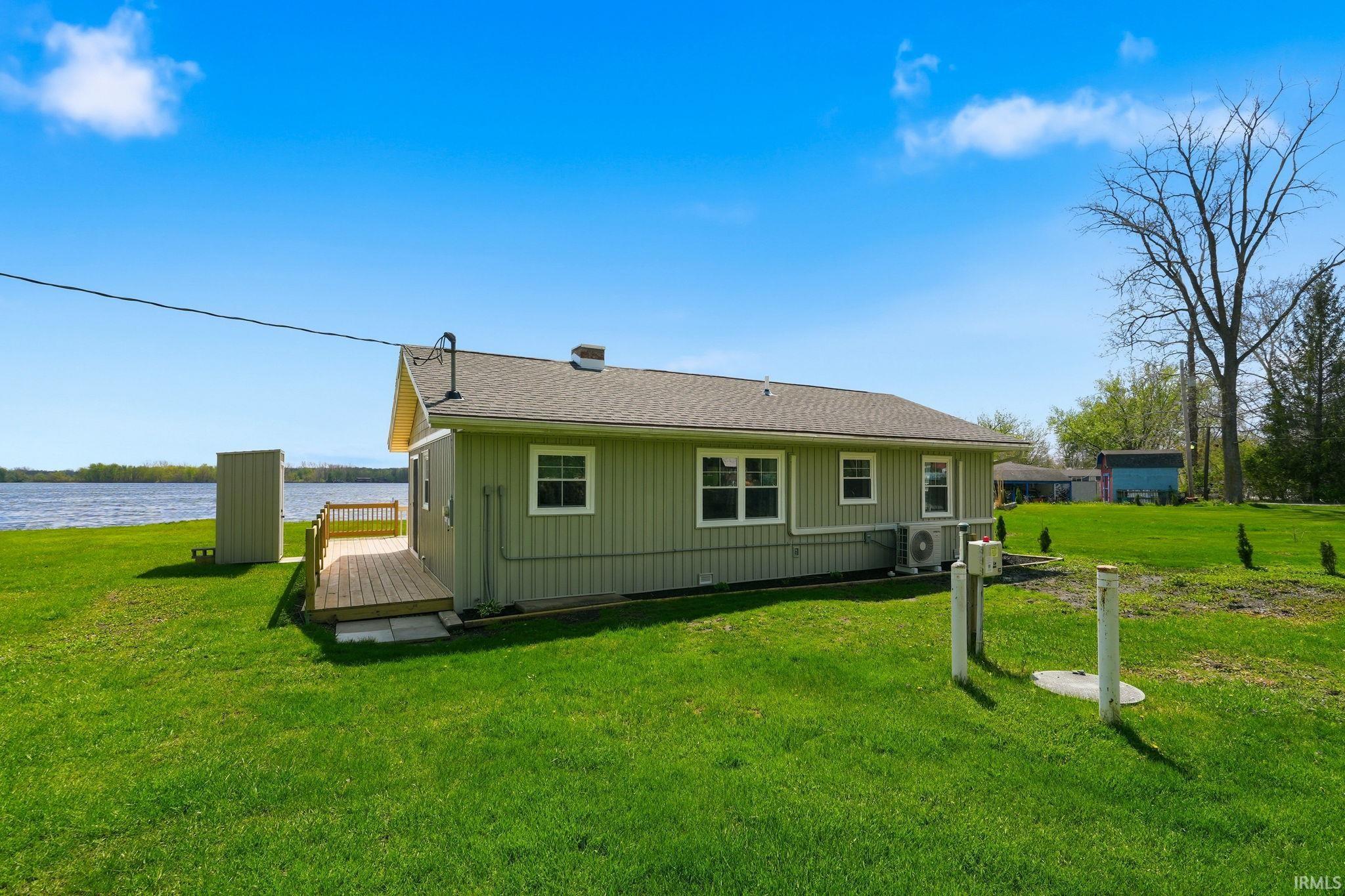 Waterfront property featuring a wood deck, green siding, and a manicured lawn