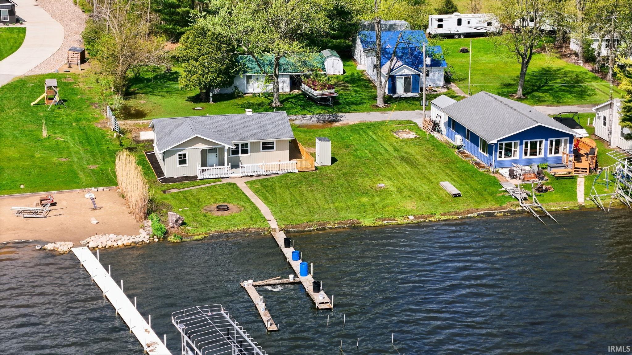 Waterfront property featuring a private sandy beach area, a long private dock, and a secondary dock with boat lift