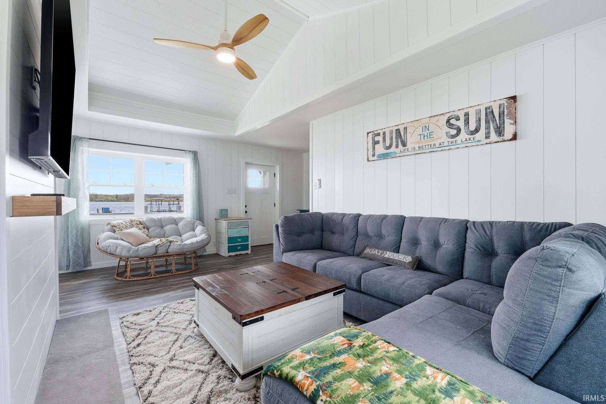Open-concept living space featuring wood-finish flooring and a tray ceiling with a modern ceiling fan