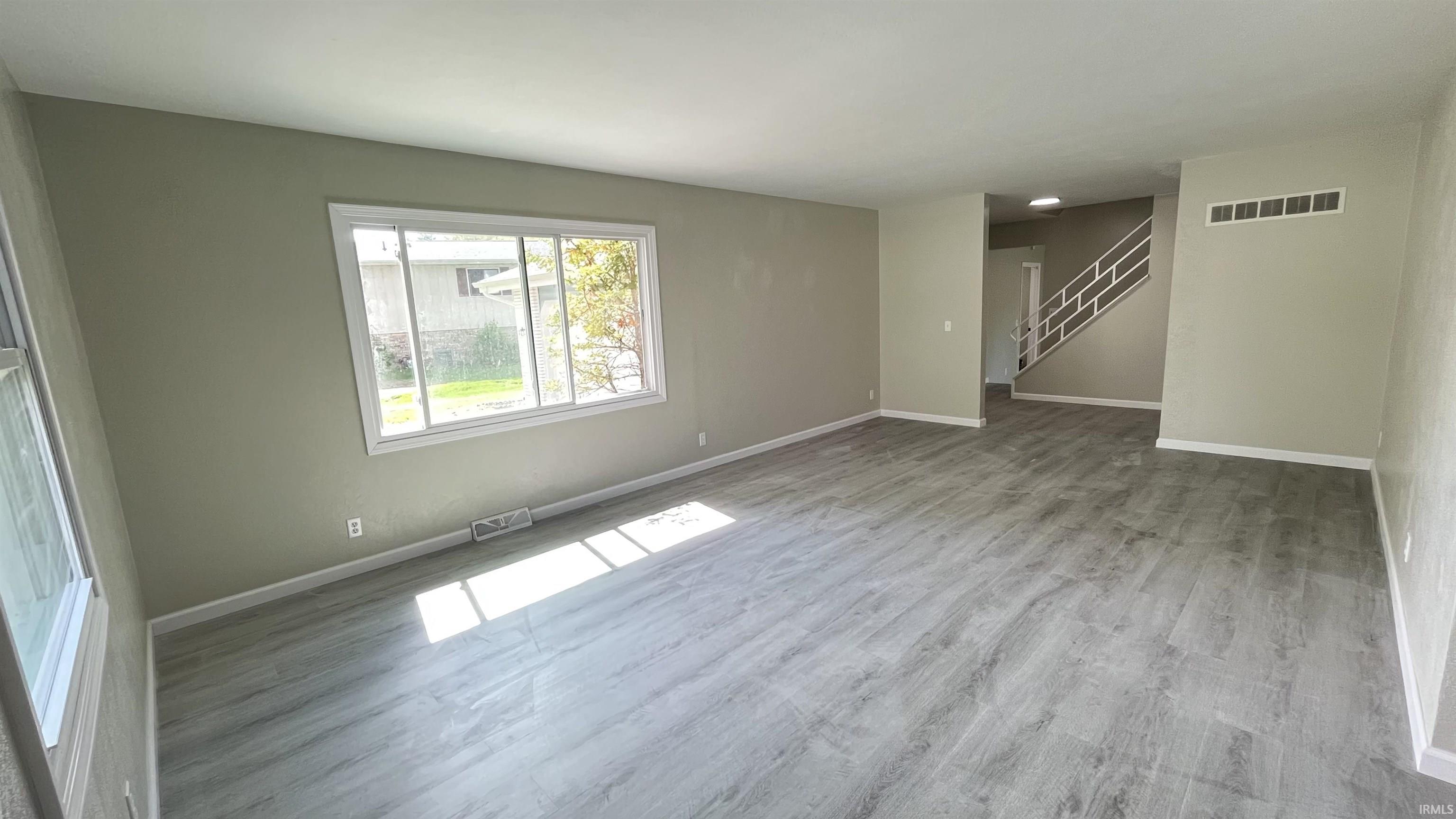 Spacious room featuring light gray walls and wood-finish flooring