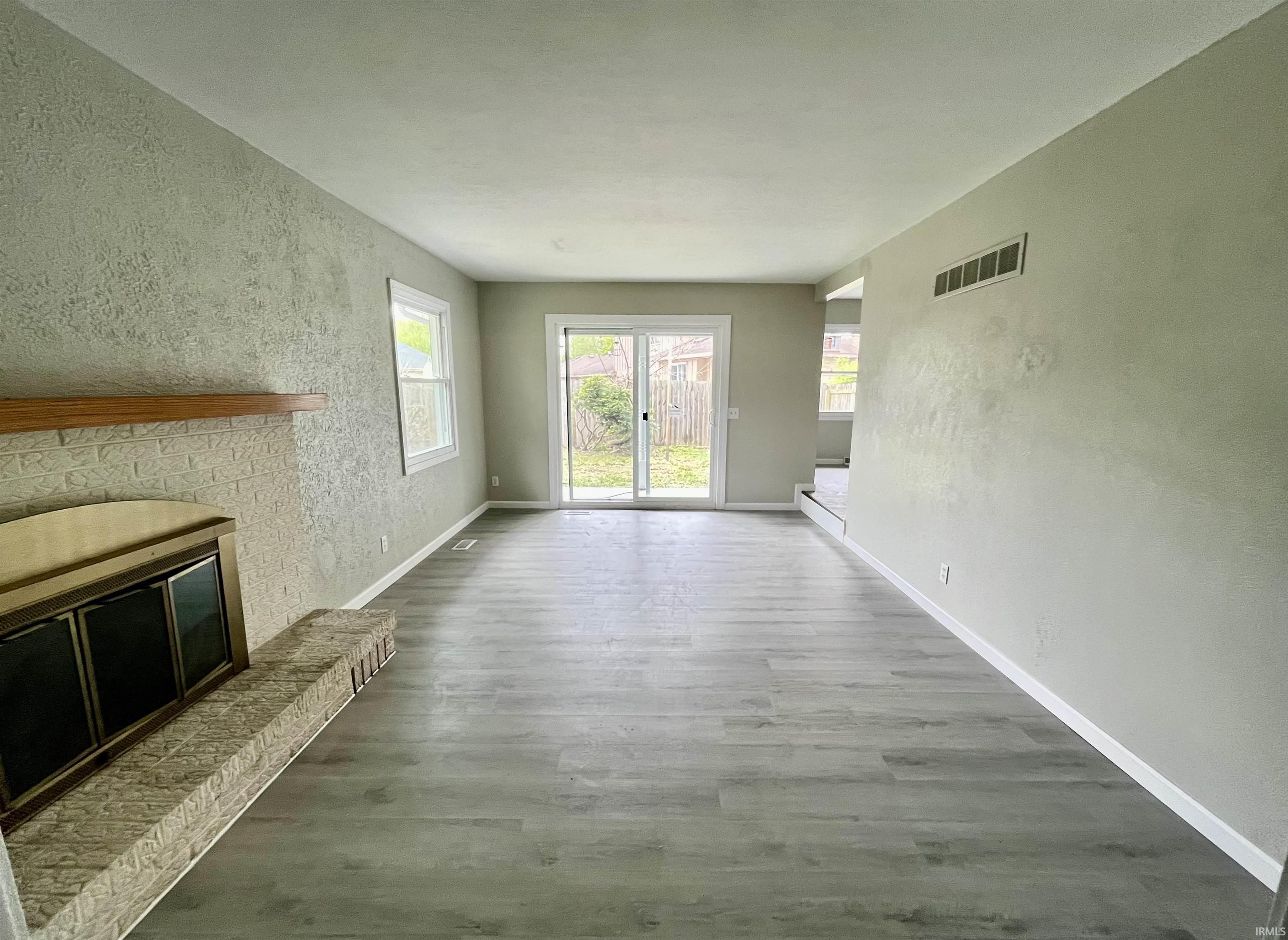 Living area featuring wood-finish flooring, a brick fireplace with a wood mantle, and sliding glass doors to the exterior
