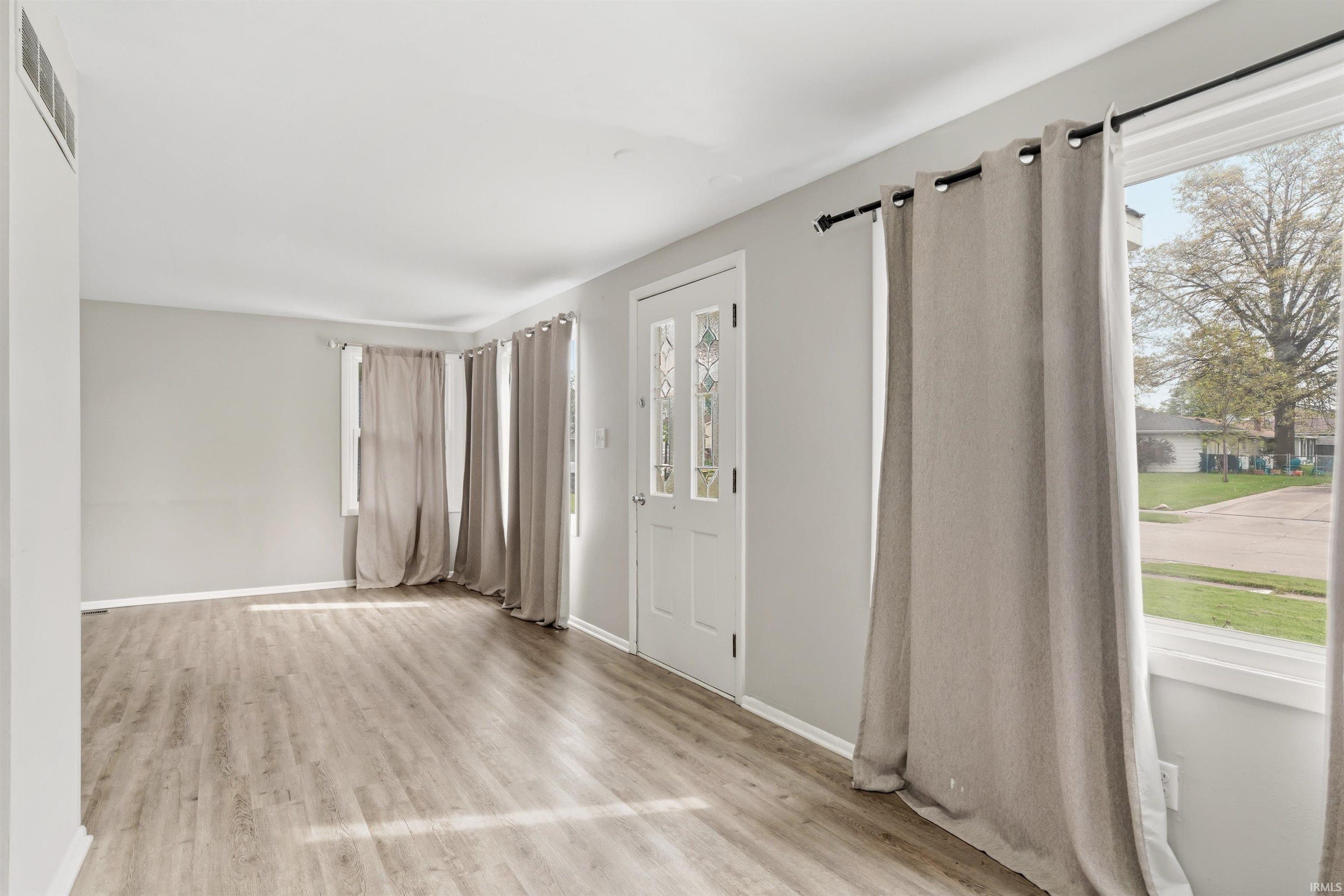 Entryway featuring a white door with decorative glass inserts, wood-finish flooring, and light gray wall paint