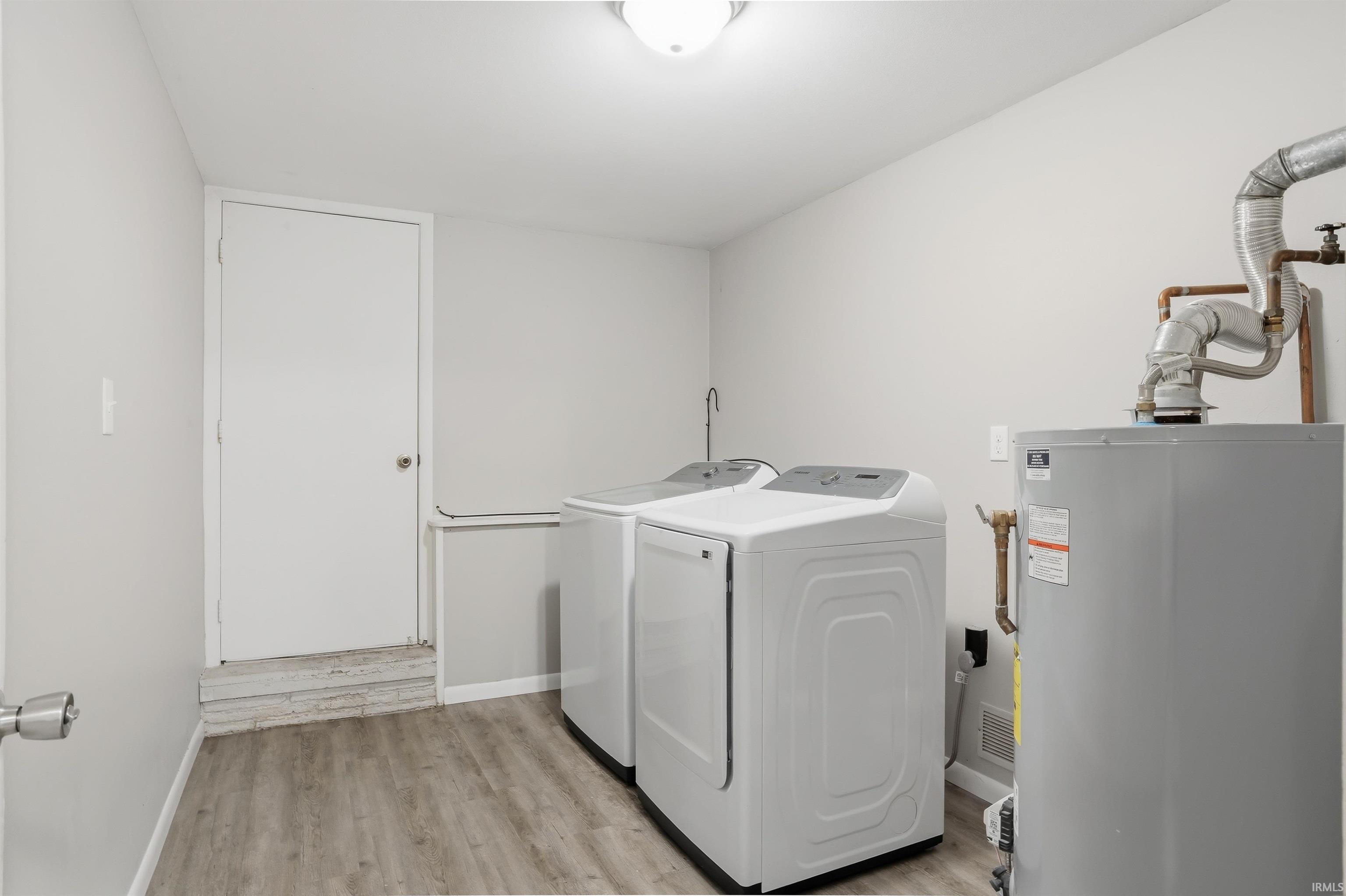 Dedicated laundry area featuring a water heater, utility sink, and wood-finish flooring