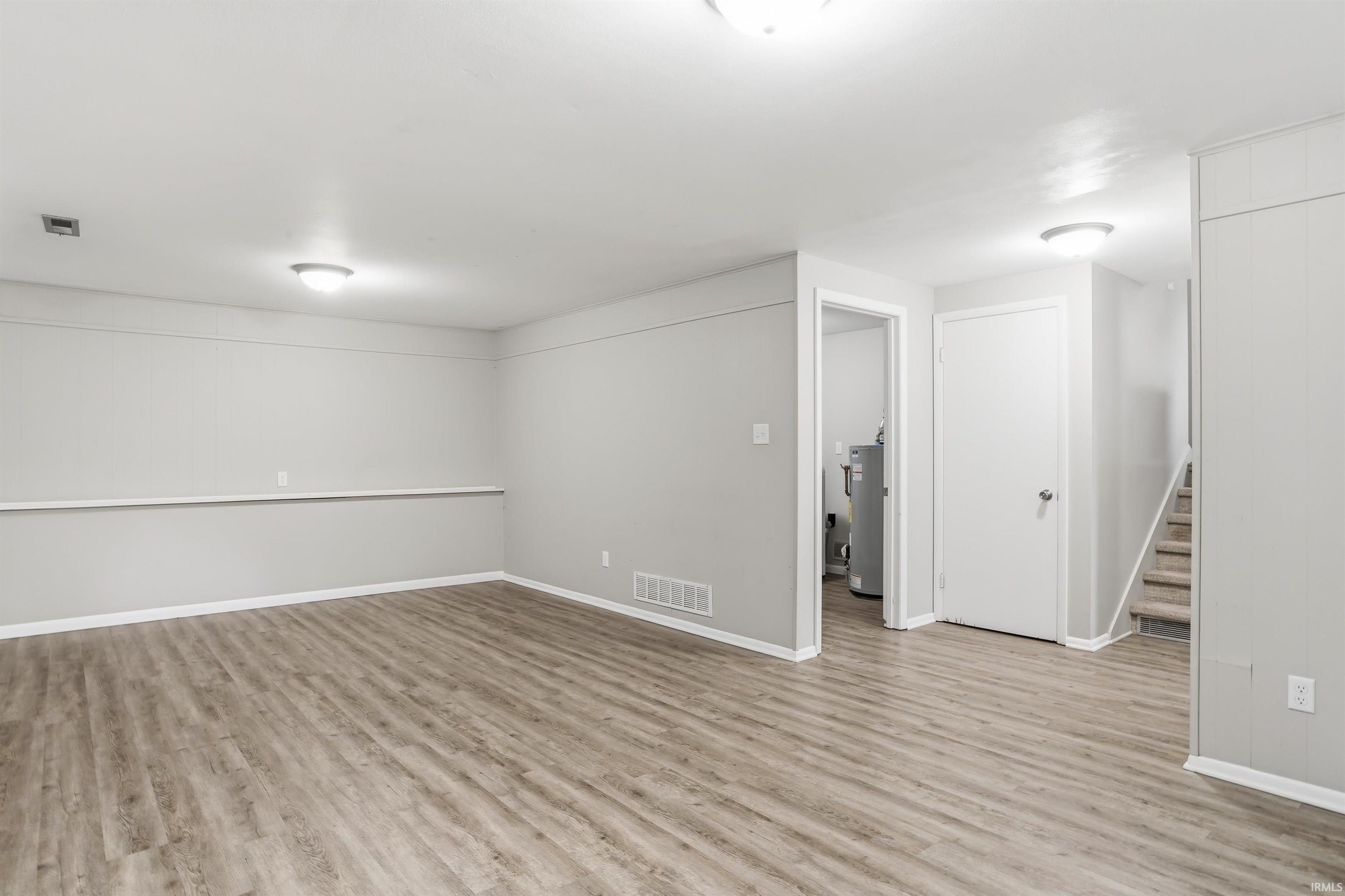 Finished room featuring wood-finish flooring, light gray wall paint, white trim, and flush-mount ceiling lighting