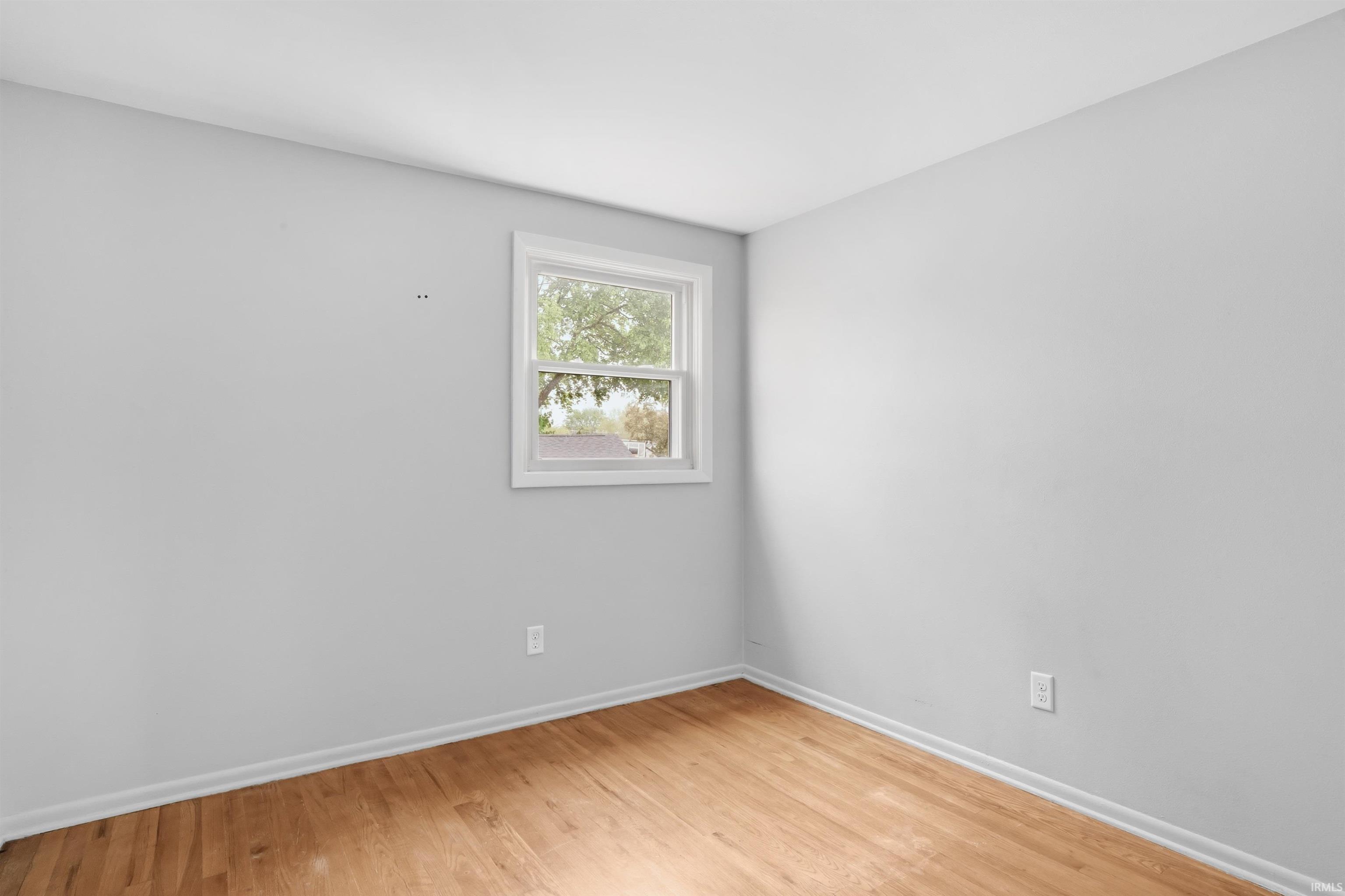 Room featuring wood-finish flooring, light gray wall paint, and white trim