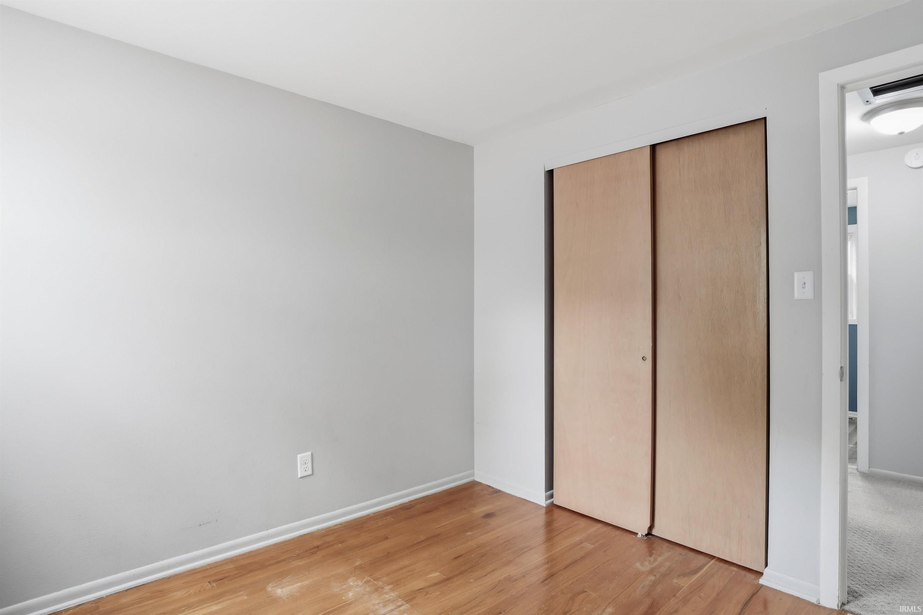 Room featuring wood-finish flooring, light gray wall paint, and white baseboards