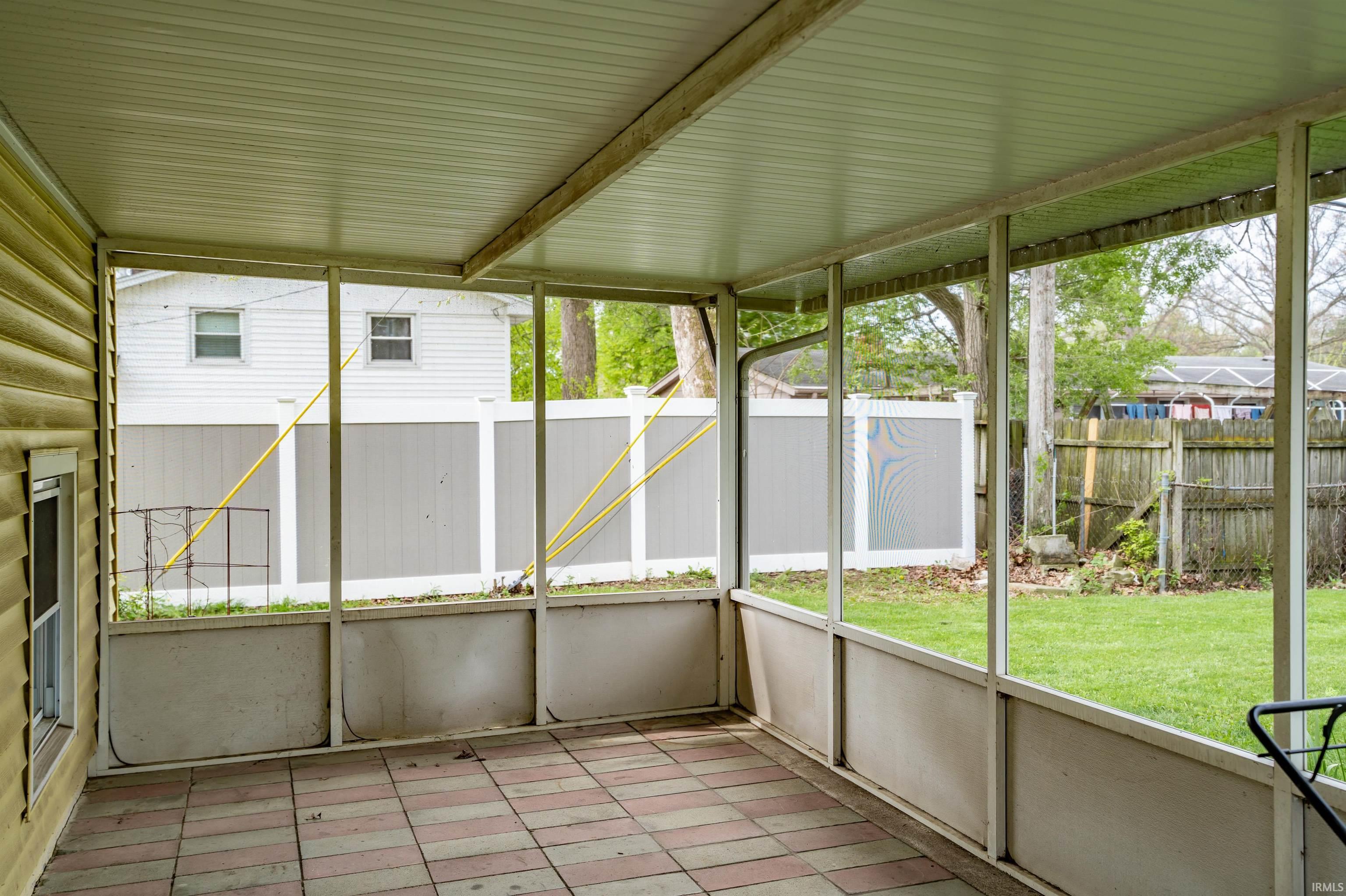 Screened patio featuring a solid roof, tiled flooring, and exterior siding