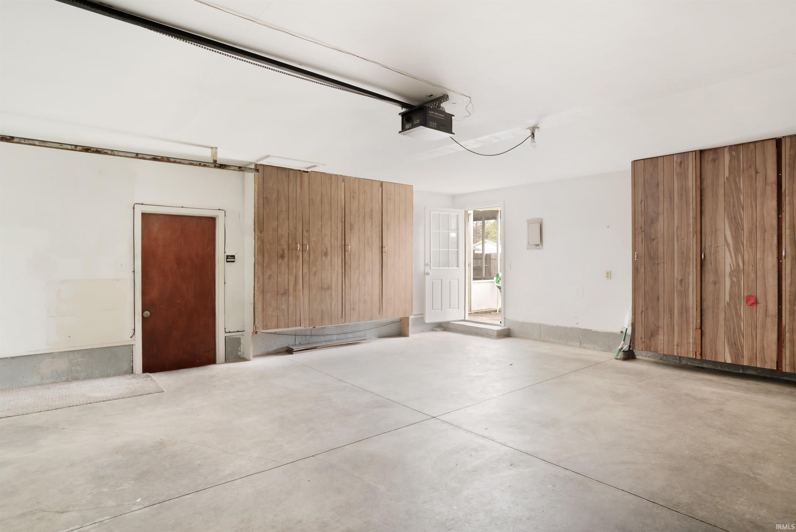 Spacious garage featuring concrete flooring and extensive built-in wood-finish cabinetry