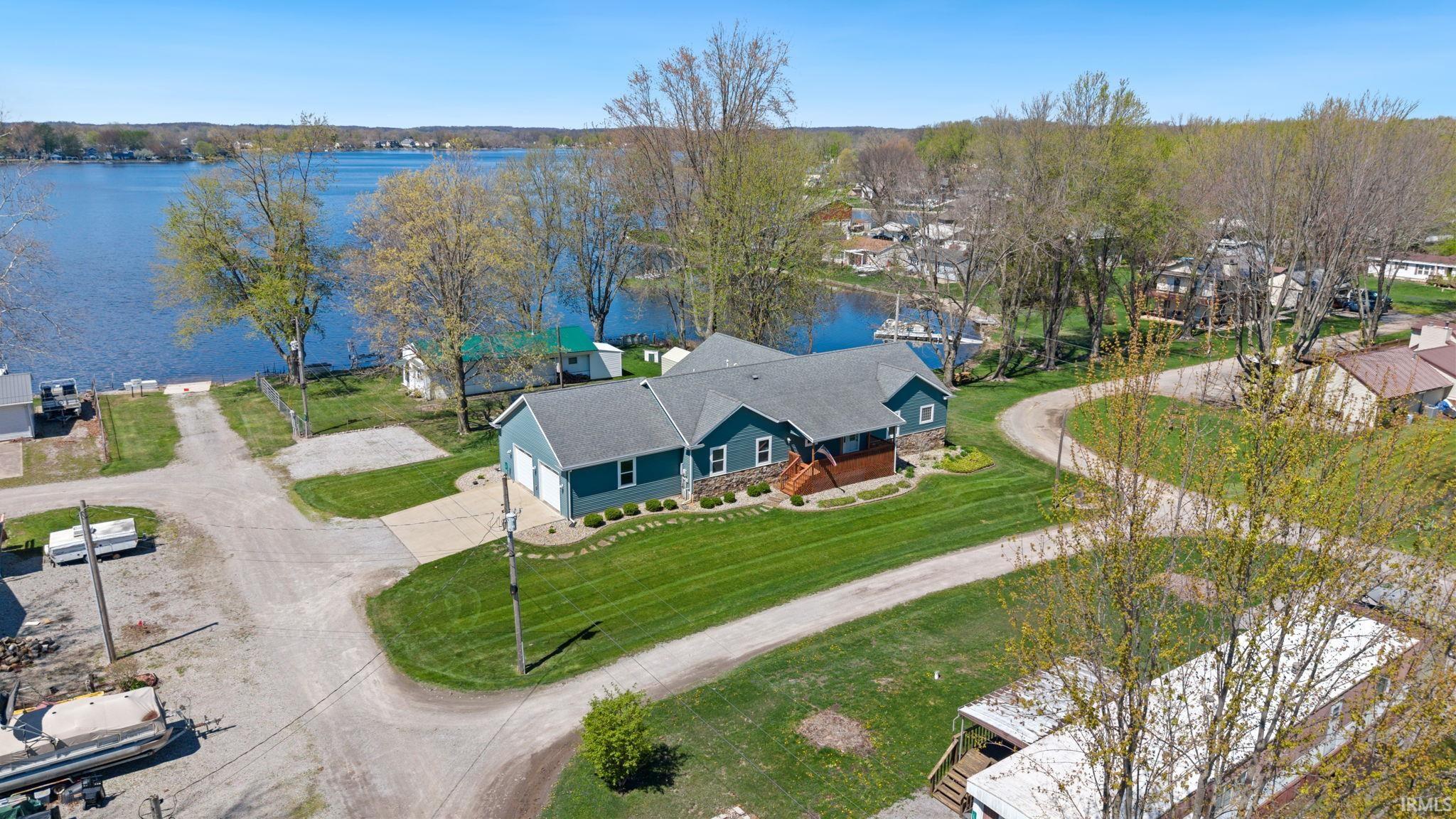 Waterfront property featuring a blue exterior, stone accents, and a brown front porch