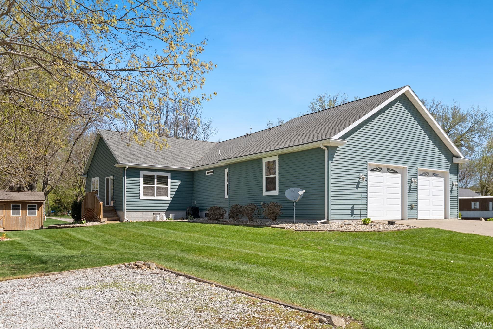 Ranch-style residence featuring blue horizontal siding, a two-car garage with white doors, and a gray shingle roof