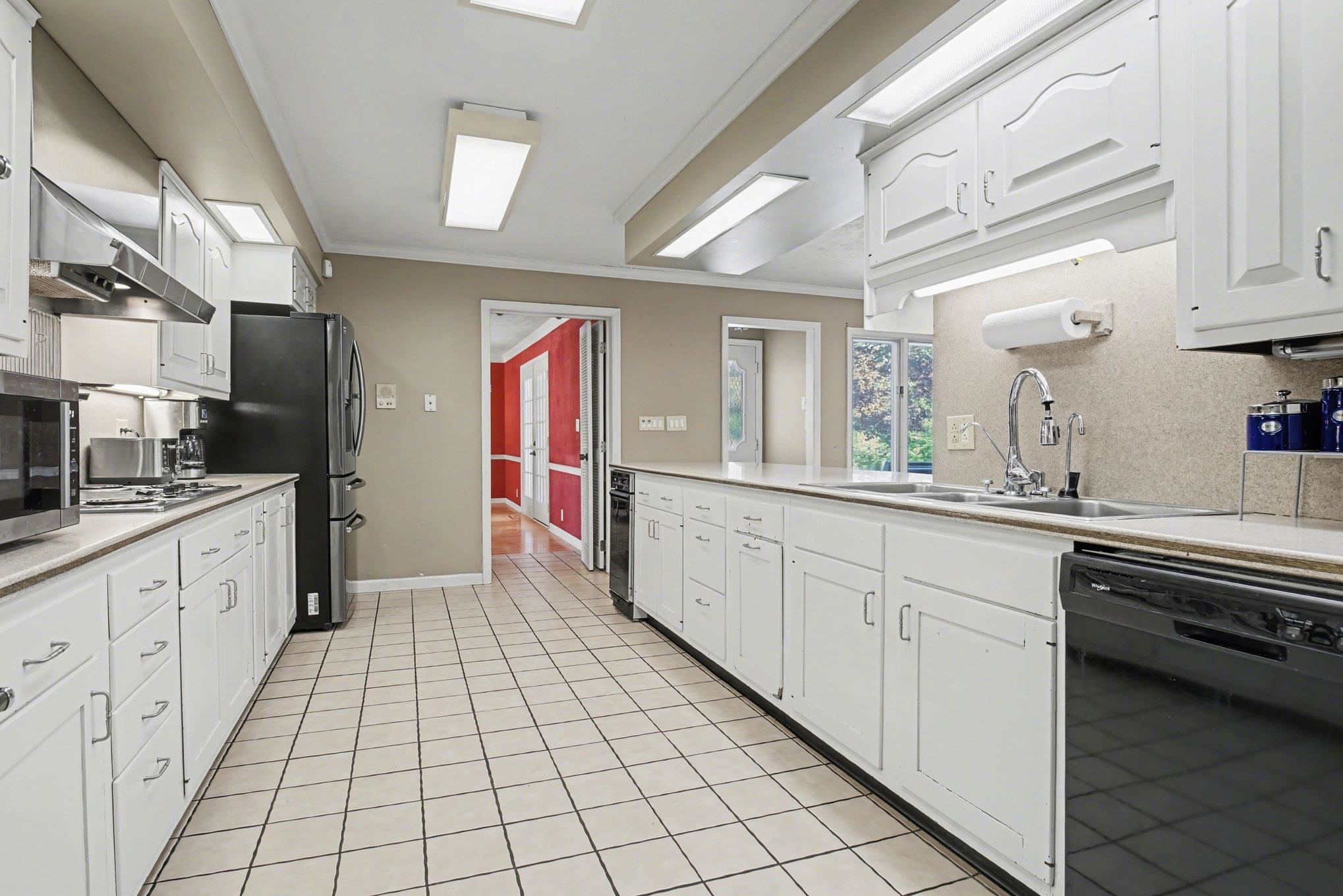 Expansive kitchen featuring white cabinetry, light-colored countertops, a tile backsplash, and tile flooring