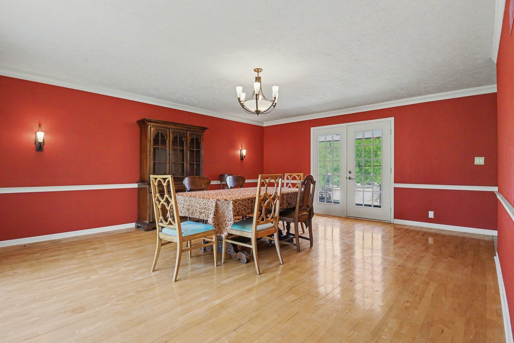 Dining area featuring light wood-finish flooring, white crown molding, and a central chandelier