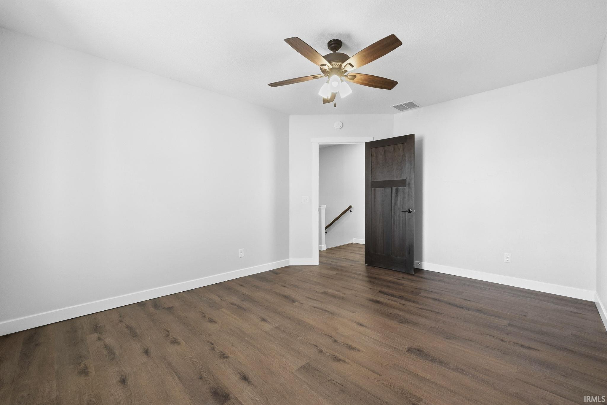 Empty room featuring dark wood-style floors and ceiling fan
