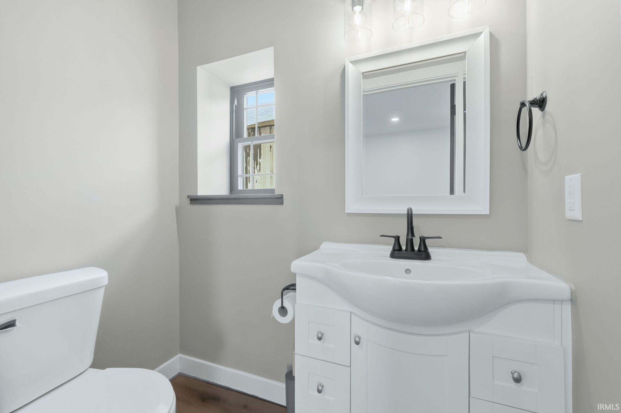 Half bathroom featuring vanity and dark wood-style flooring