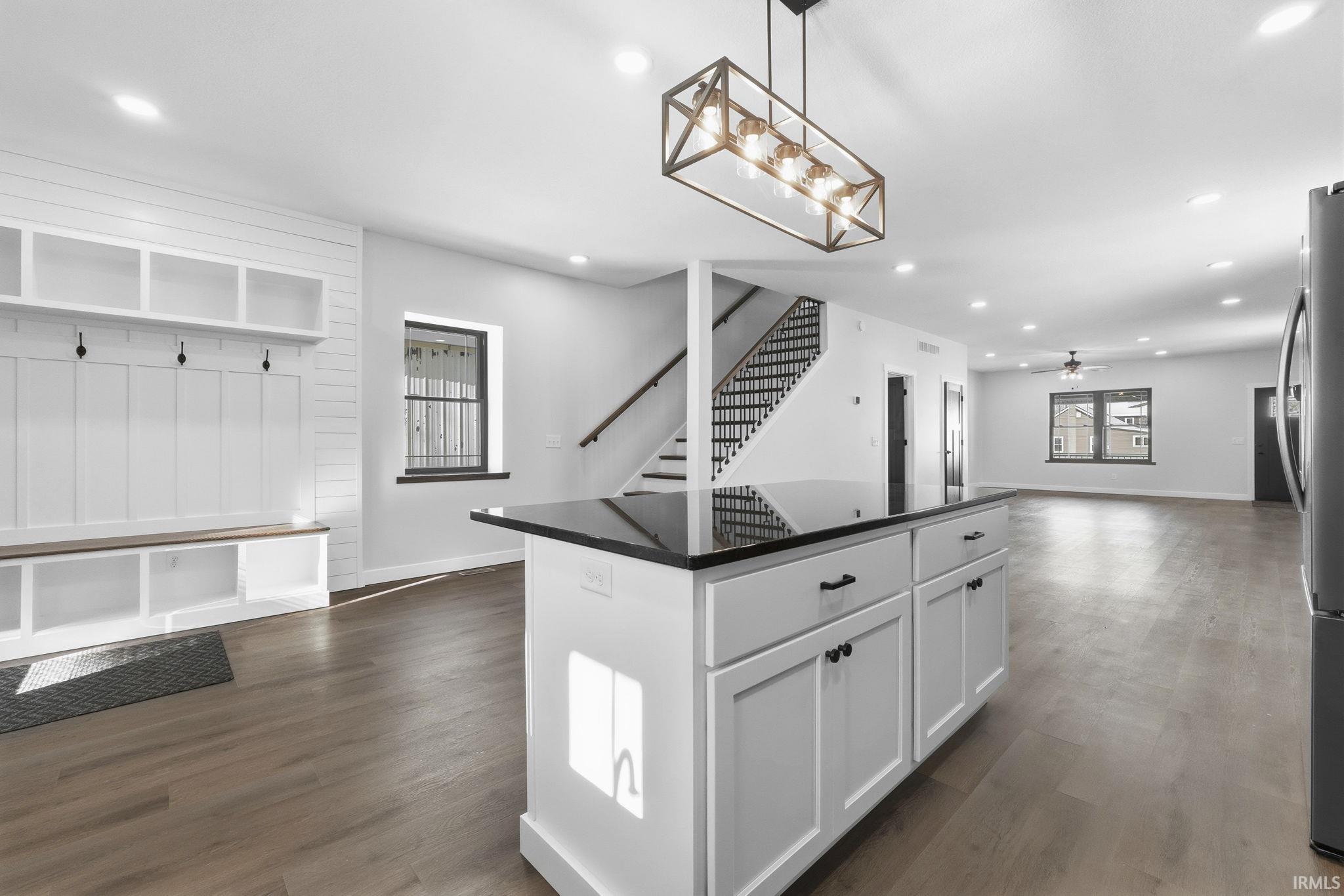 Kitchen with white cabinets, open floor plan, a center island, decorative light fixtures, and dark wood-style floors