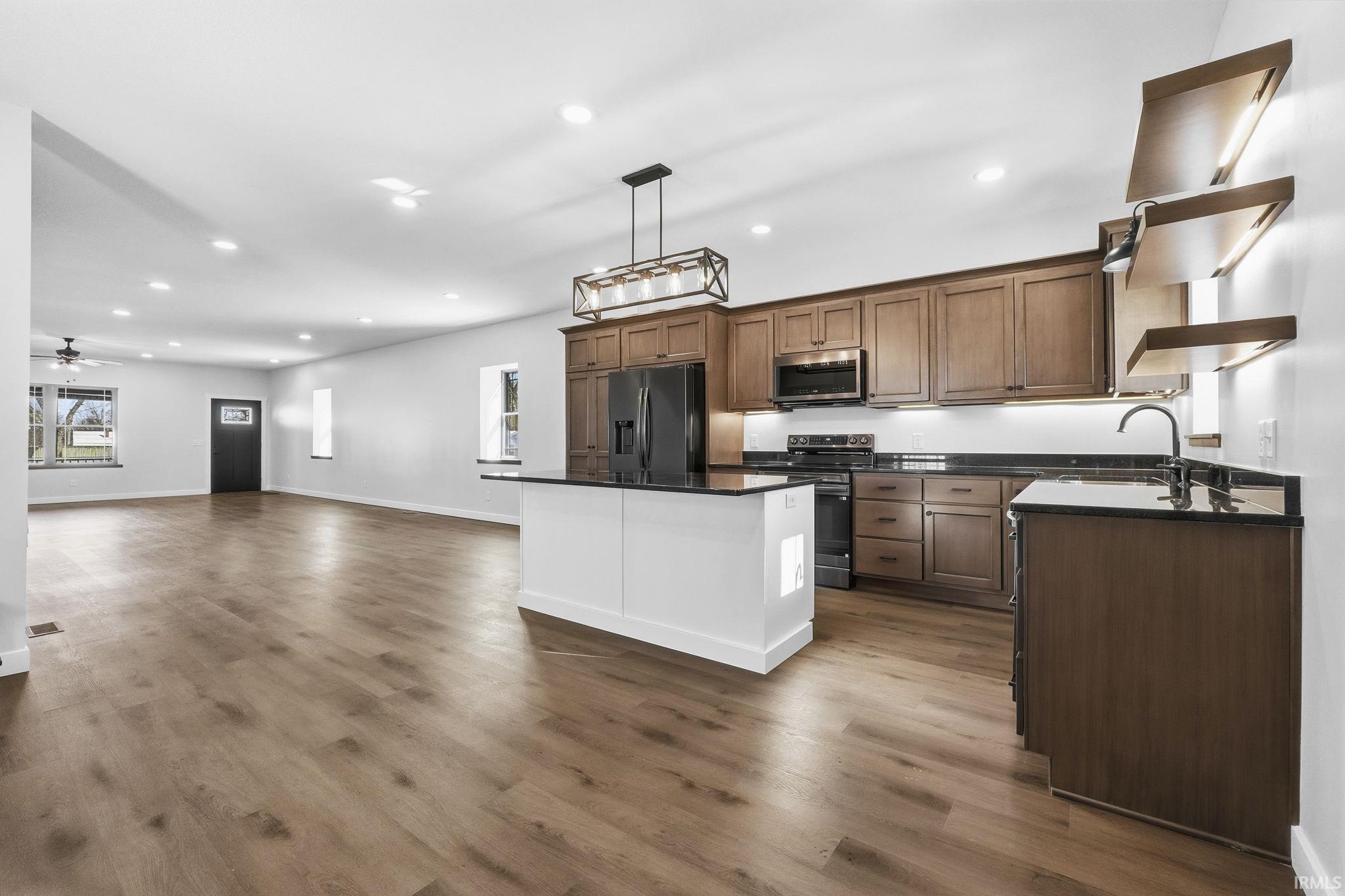 Kitchen featuring open floor plan, stainless steel appliances, open shelves, recessed lighting, and decorative light fixtures
