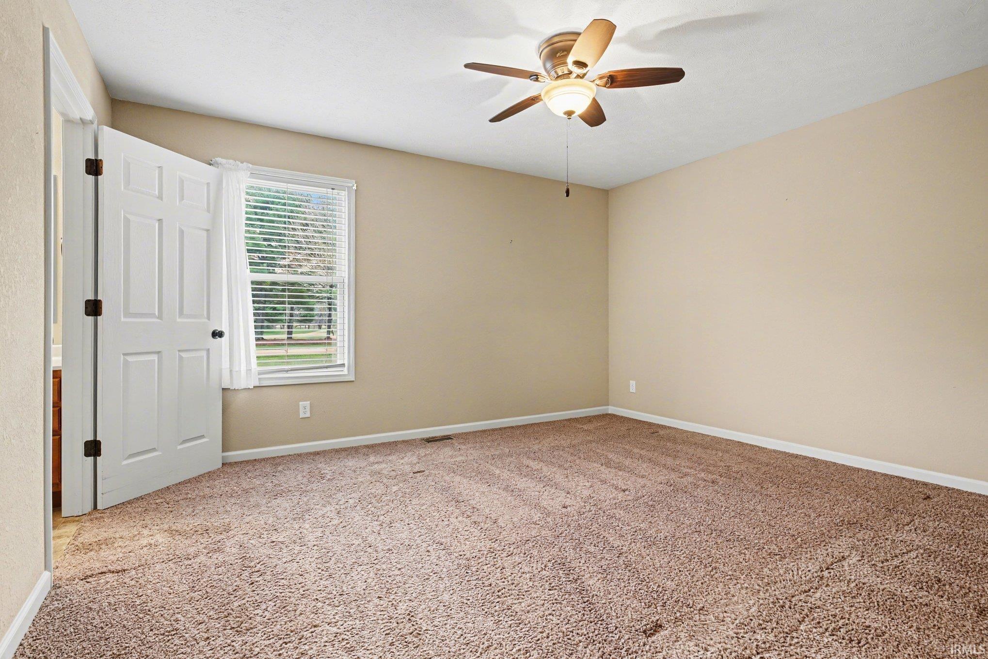Empty room with light colored carpet and ceiling fan