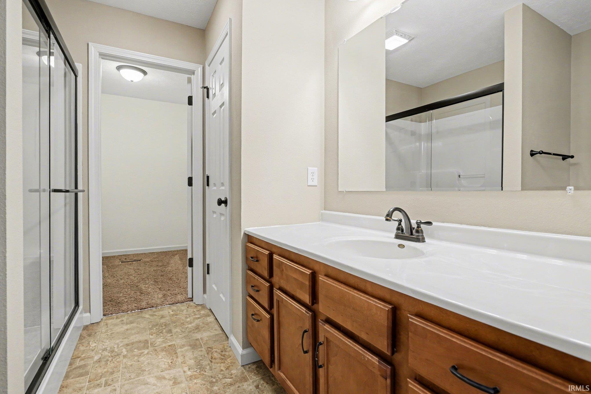 Bathroom with vanity, a shower stall, and stone finish floors