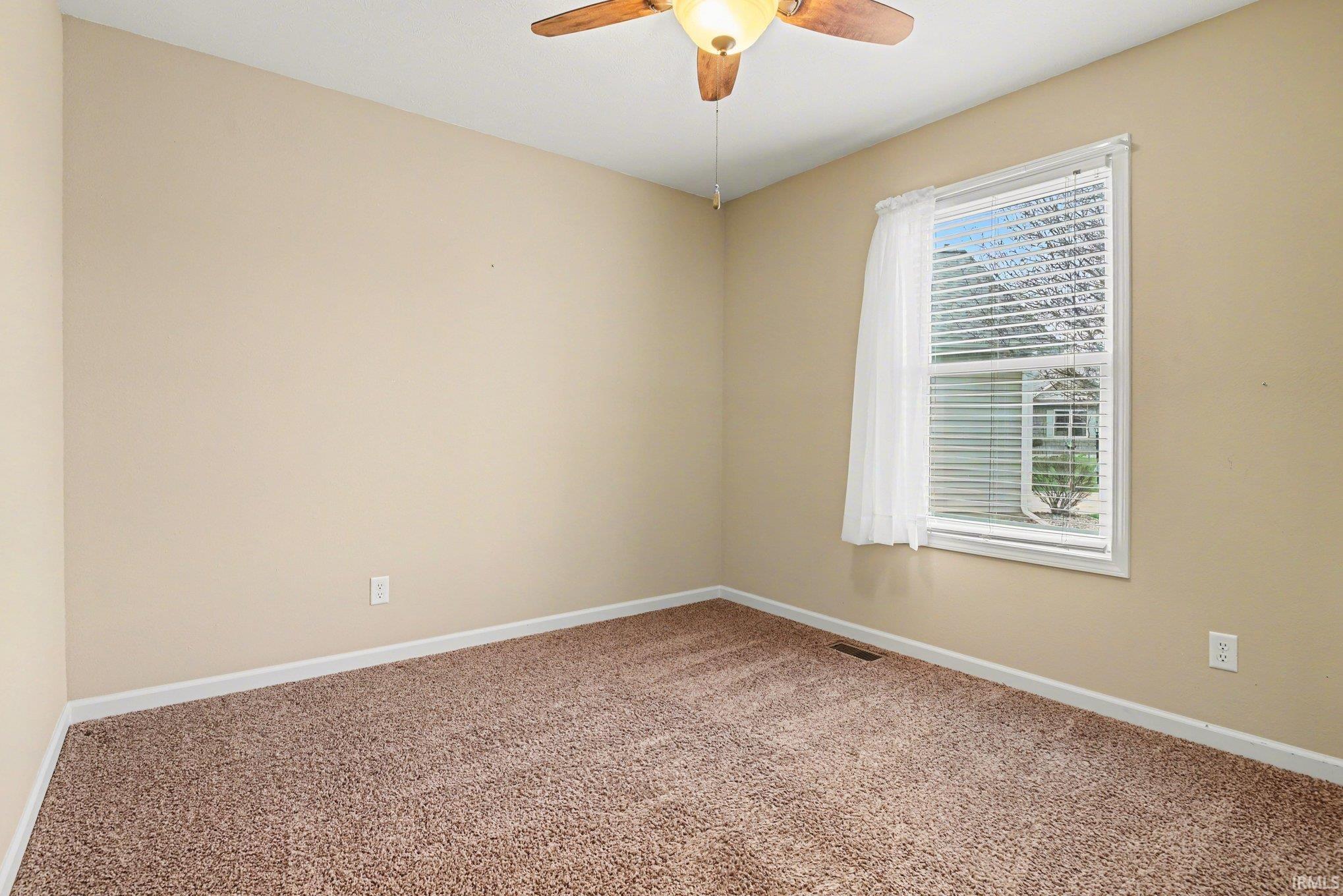 Carpeted empty room featuring baseboards and a ceiling fan