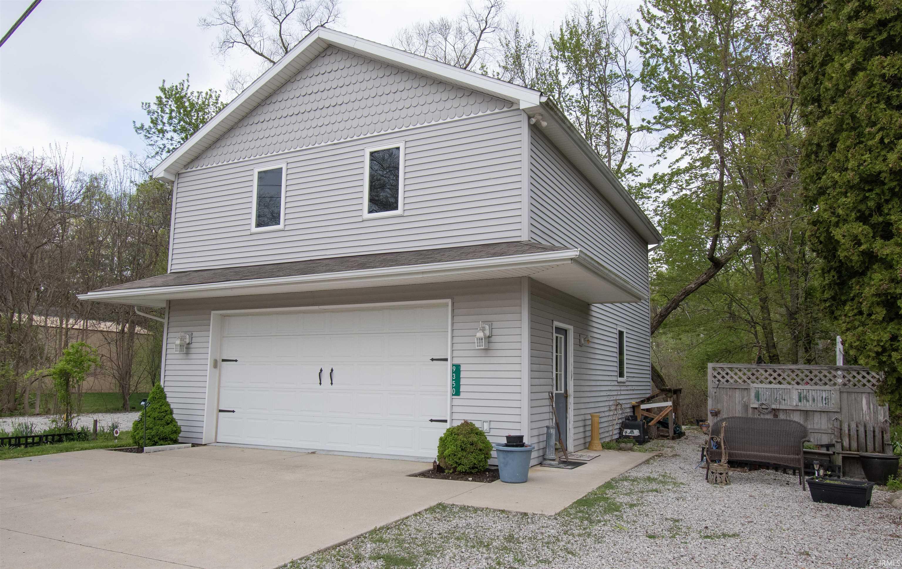 Two-story structure featuring light grey horizontal siding with a decorative shake-style gable accent