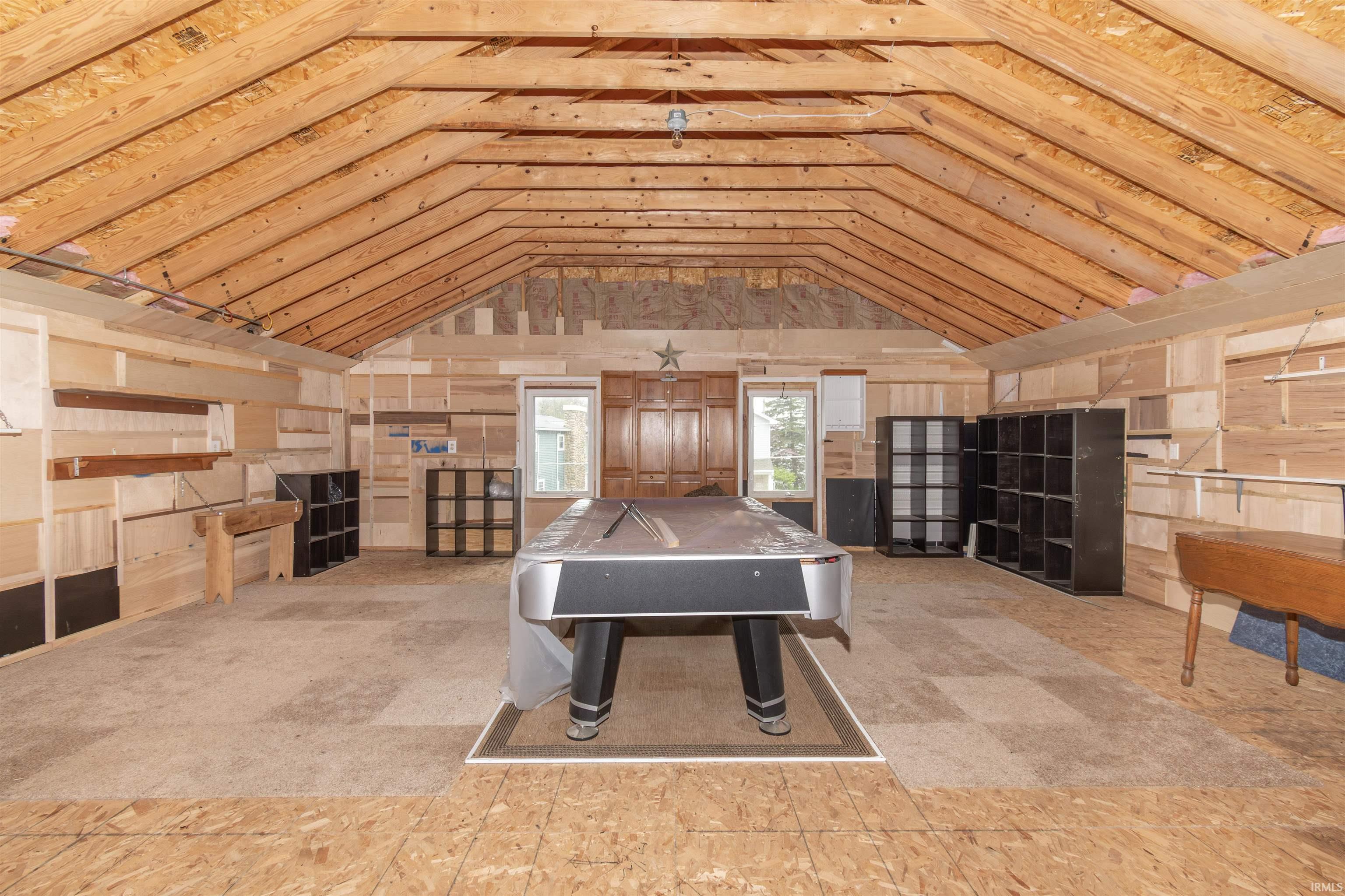 Spacious attic room with exposed wood ceiling beams and plywood wall finishes