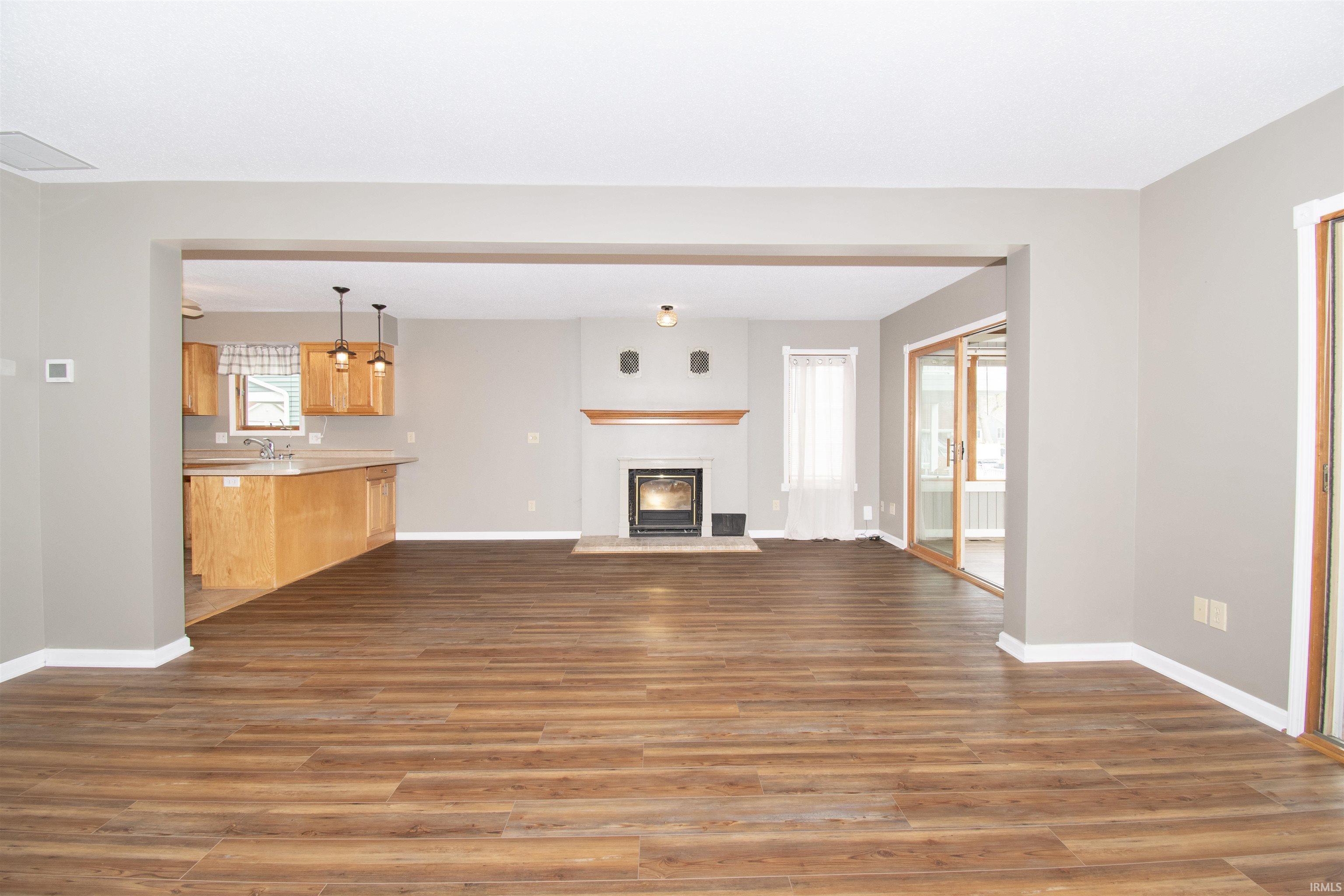 Spacious interior featuring wood-finish flooring, a modern fireplace with a wooden mantel, and light gray wall paint