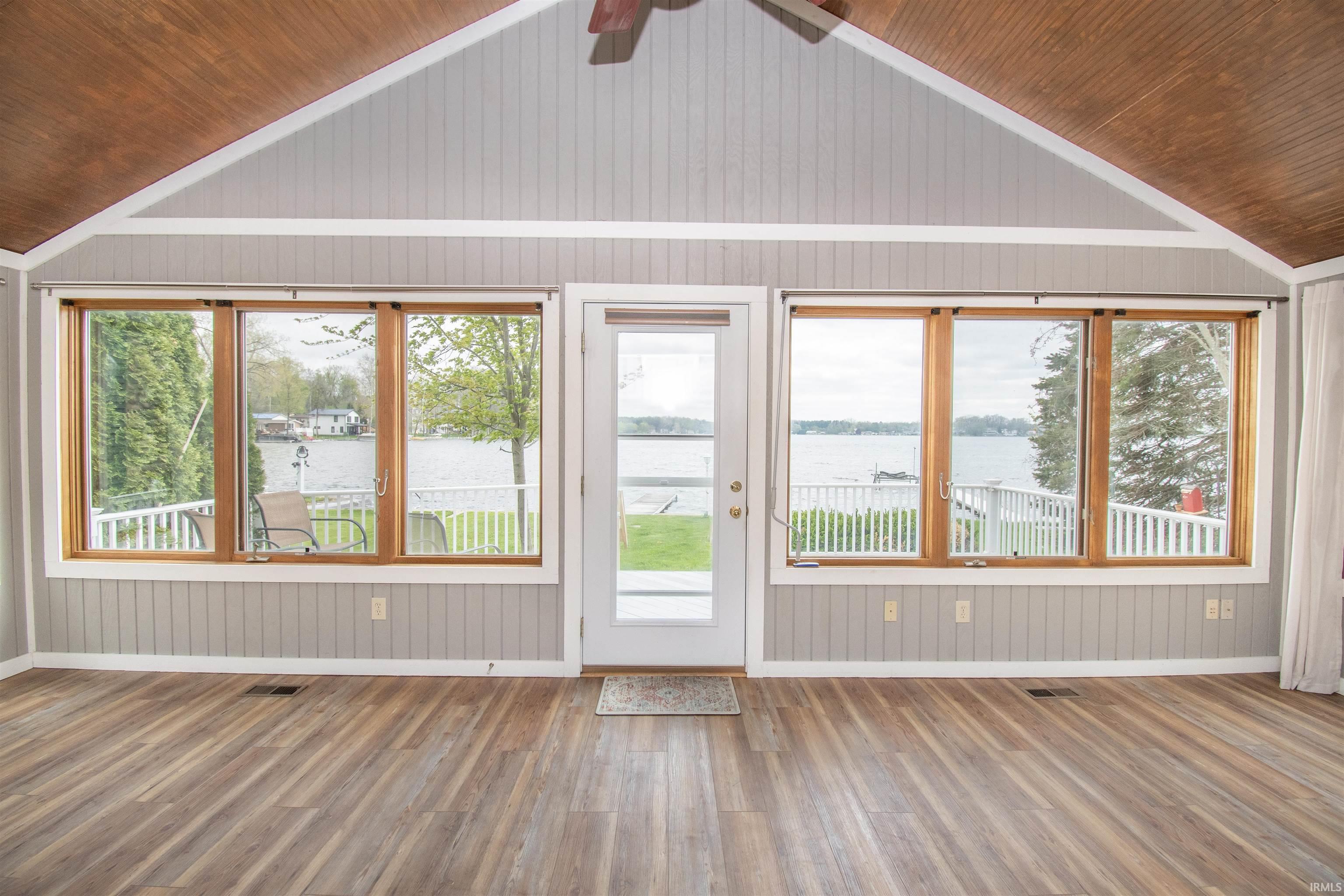 Open concept room featuring wood-finish flooring, a vaulted wood-paneled ceiling, and vertical paneling on the walls