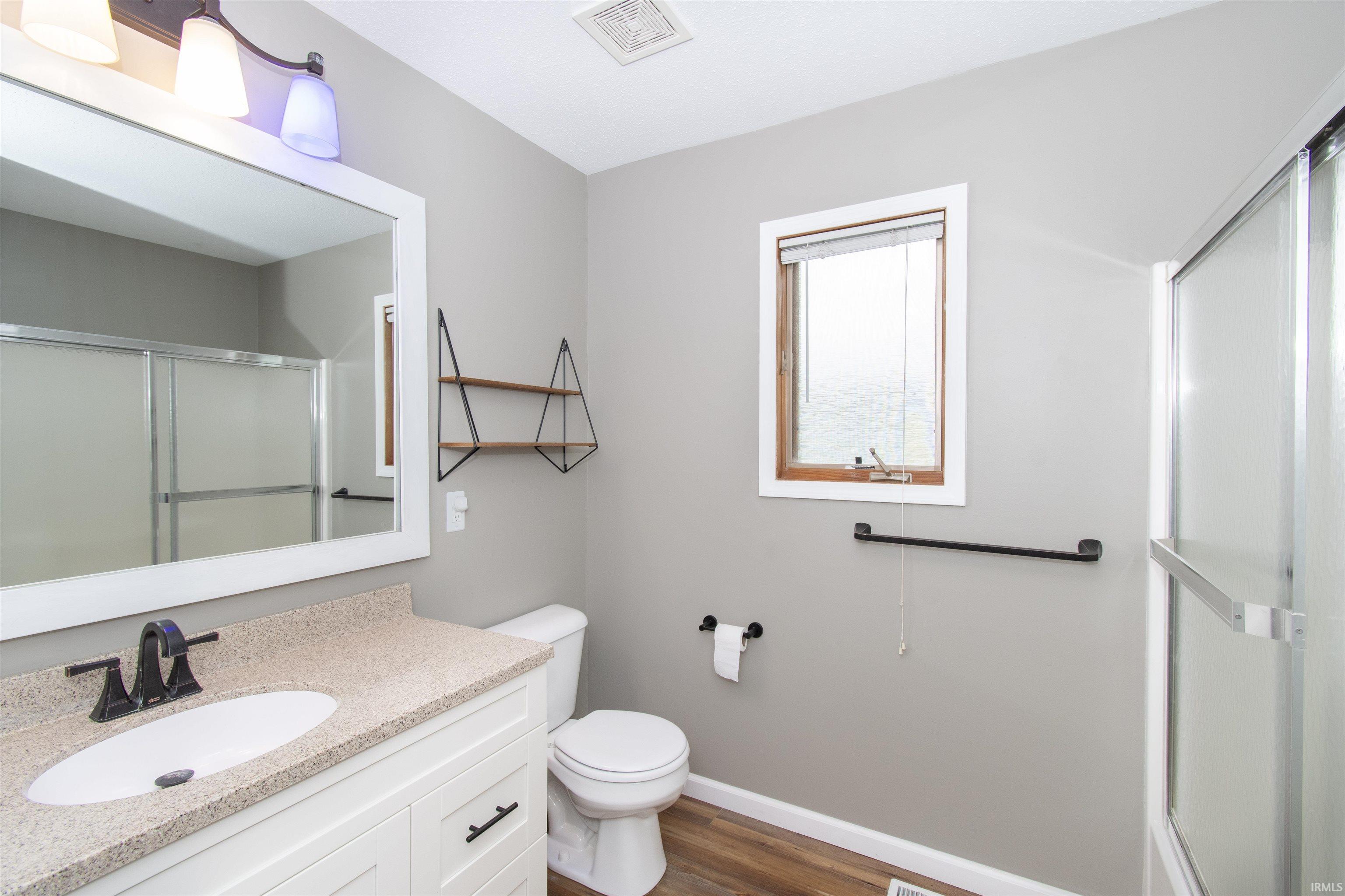 Modern bathroom featuring a white vanity with granite-style countertop and undermount sink, dark bronze faucet, and framed mirror