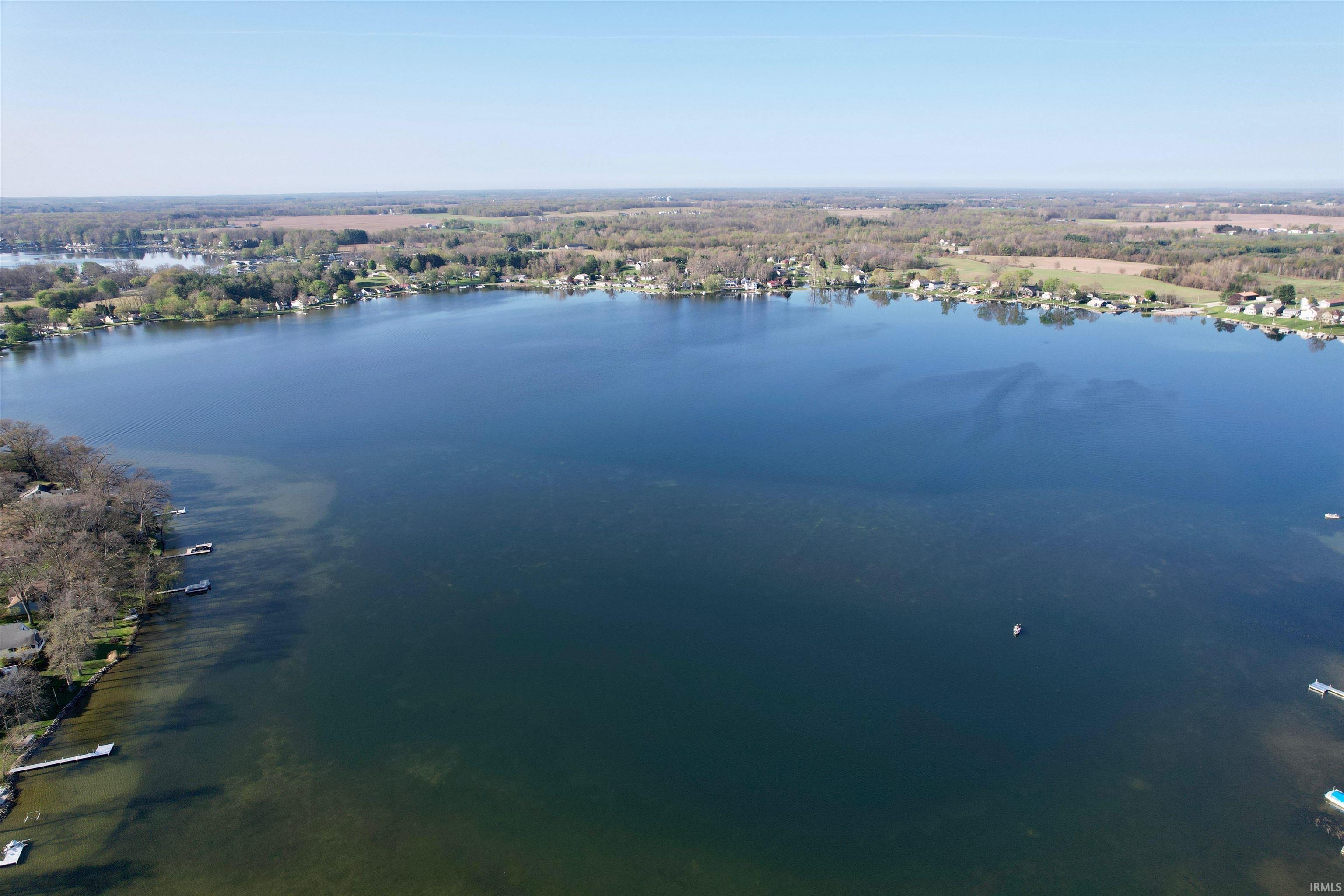 Expansive body of water bordered by wooded shorelines and residential properties