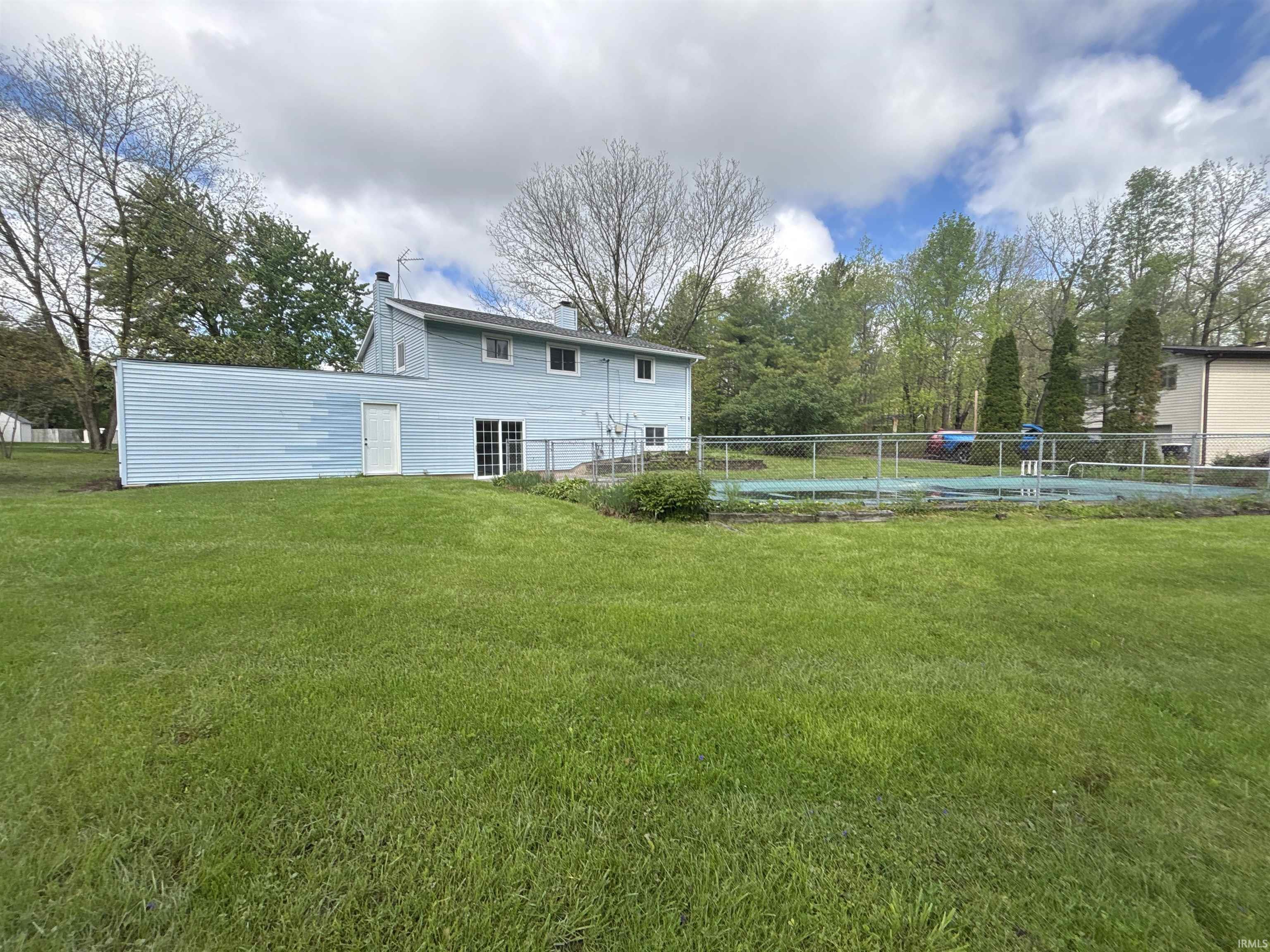 Expansive green lawn featuring a privacy-fenced in-ground swimming pool